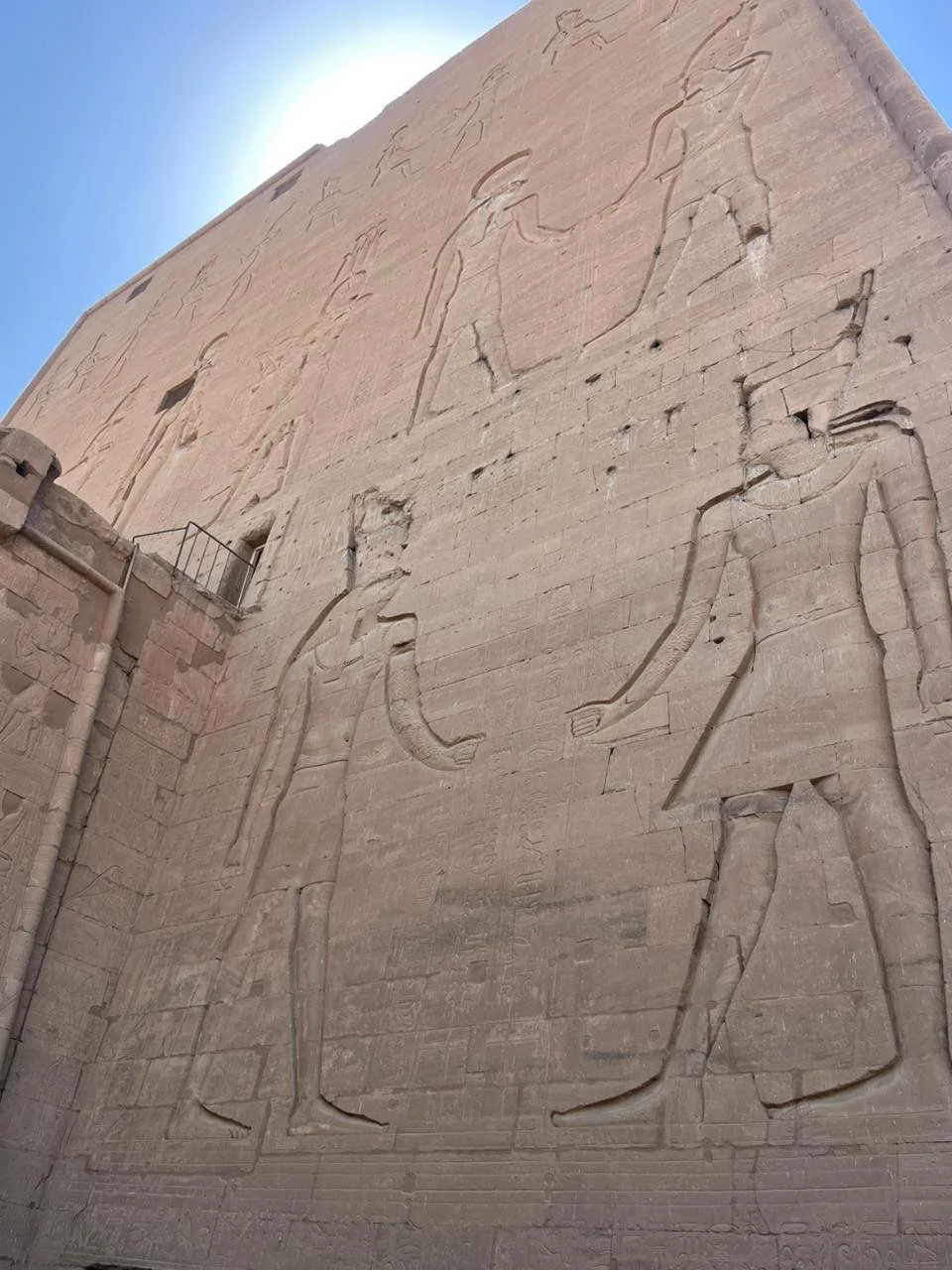 Ancient carved Egyptian hieroglyphs on a large stone wall depicting figures and symbols.