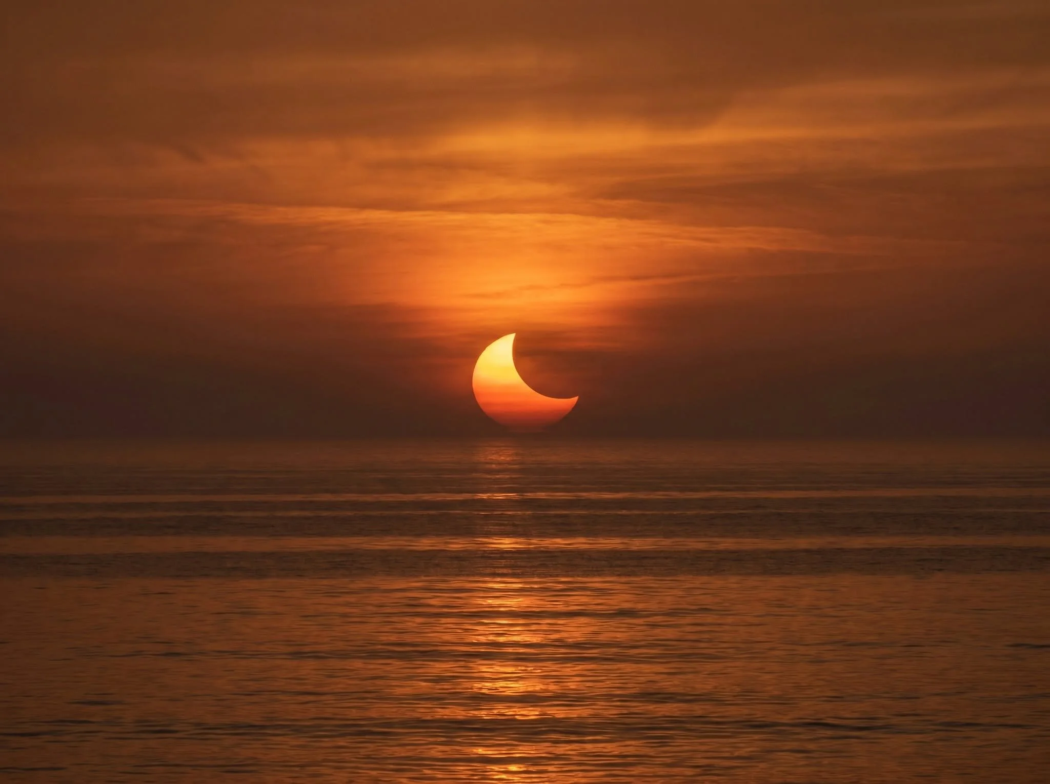 The sky during totality: darkness overhead, sunset light on every horizon.