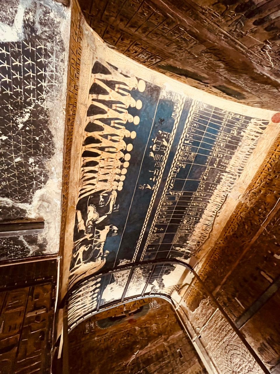 Ancient Egyptian wall painting with figures and hieroglyphics, in a dimly lit stone room.