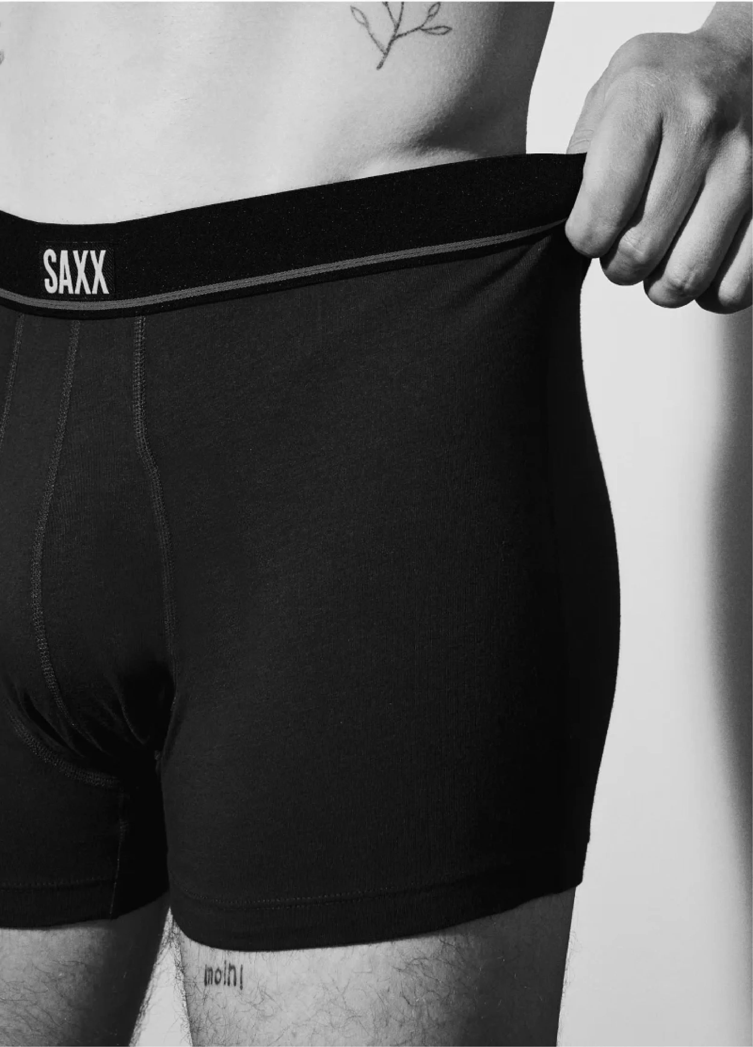 Man wearing SAXX black boxer briefs, pulling waistband