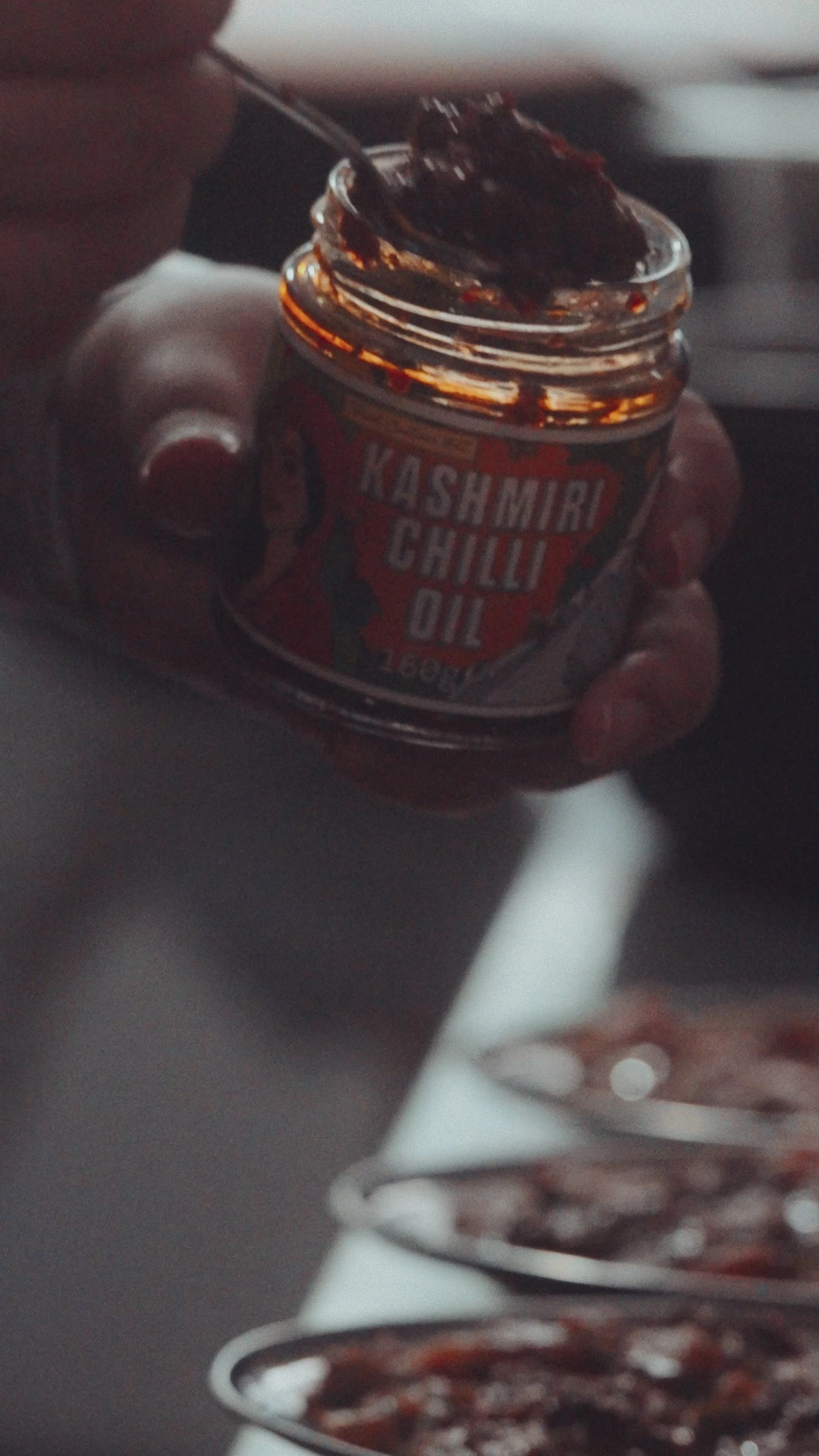 Still from the film. A jar of Saliha's TCK Kashmiri Chilli Oil being used in the cooking process.