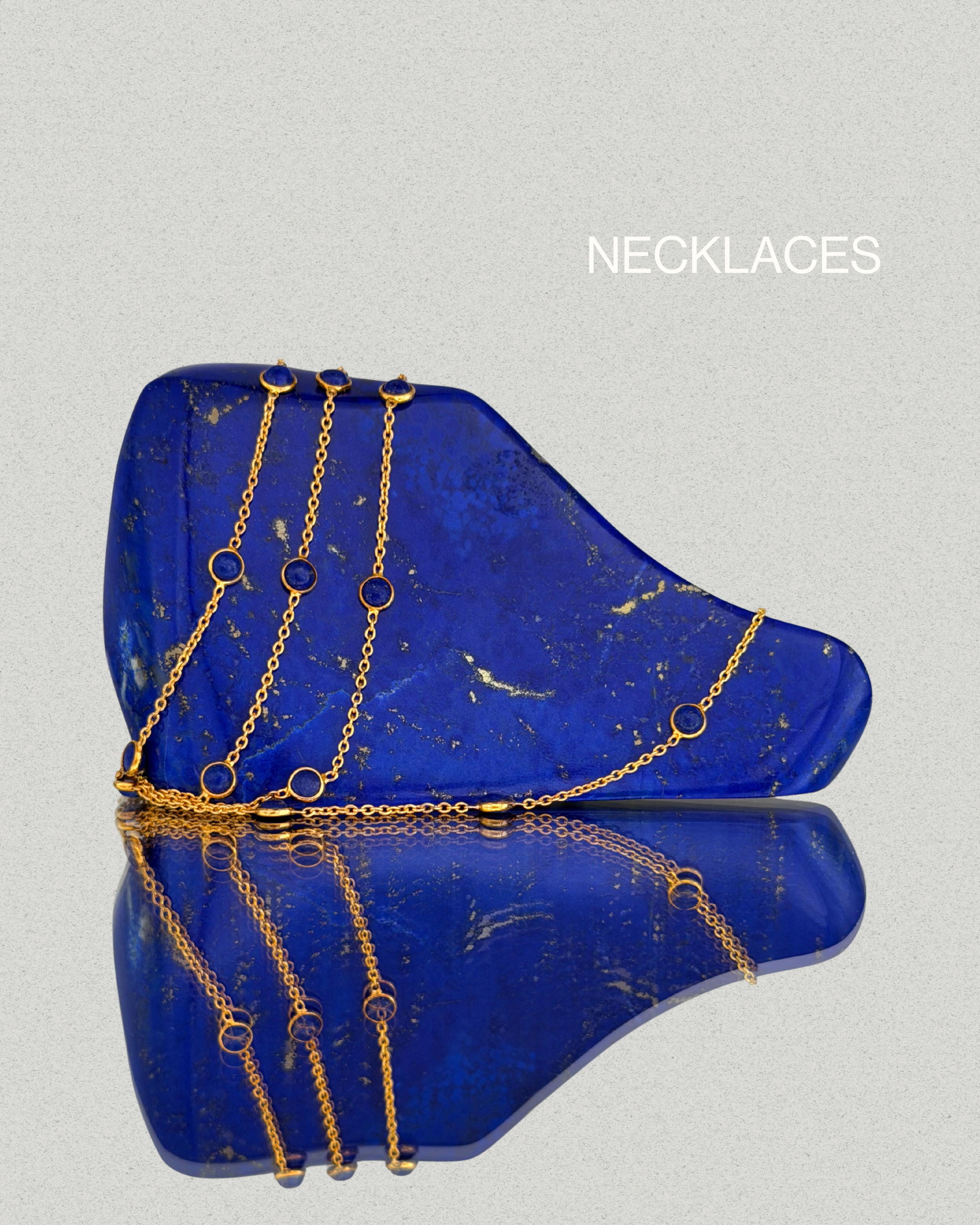 Gold necklaces from the Paivand collection draped over lapis lazuli stone with natural gold veining.