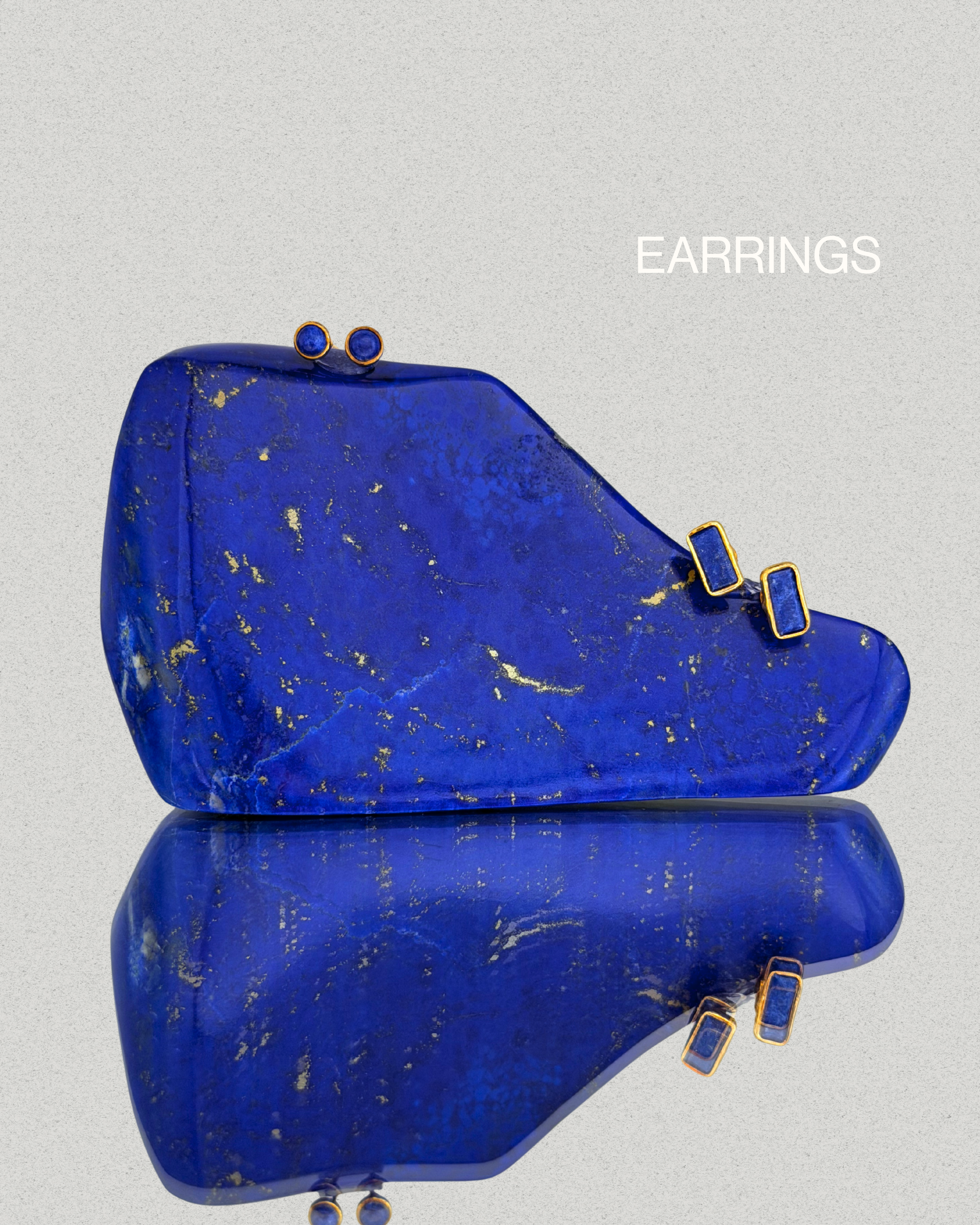 Gold earrings from the Paivand collection displayed on a lapis lazuli stone.