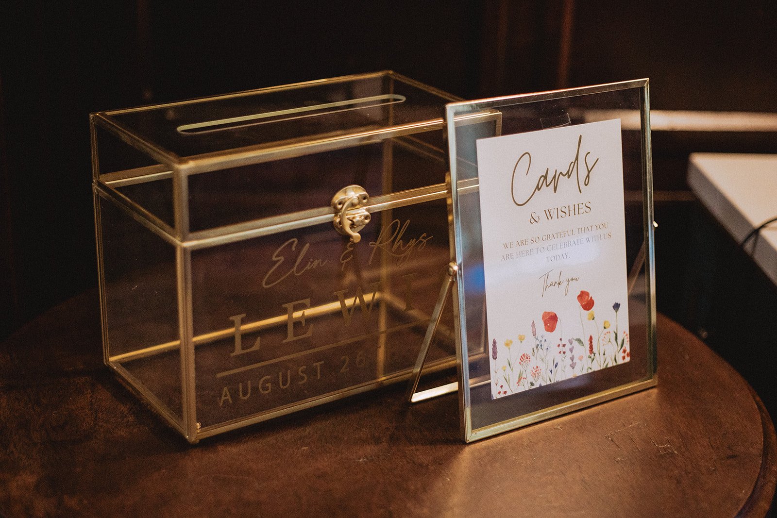 Glass card box with a "cards & wishes" sign on a wooden table.