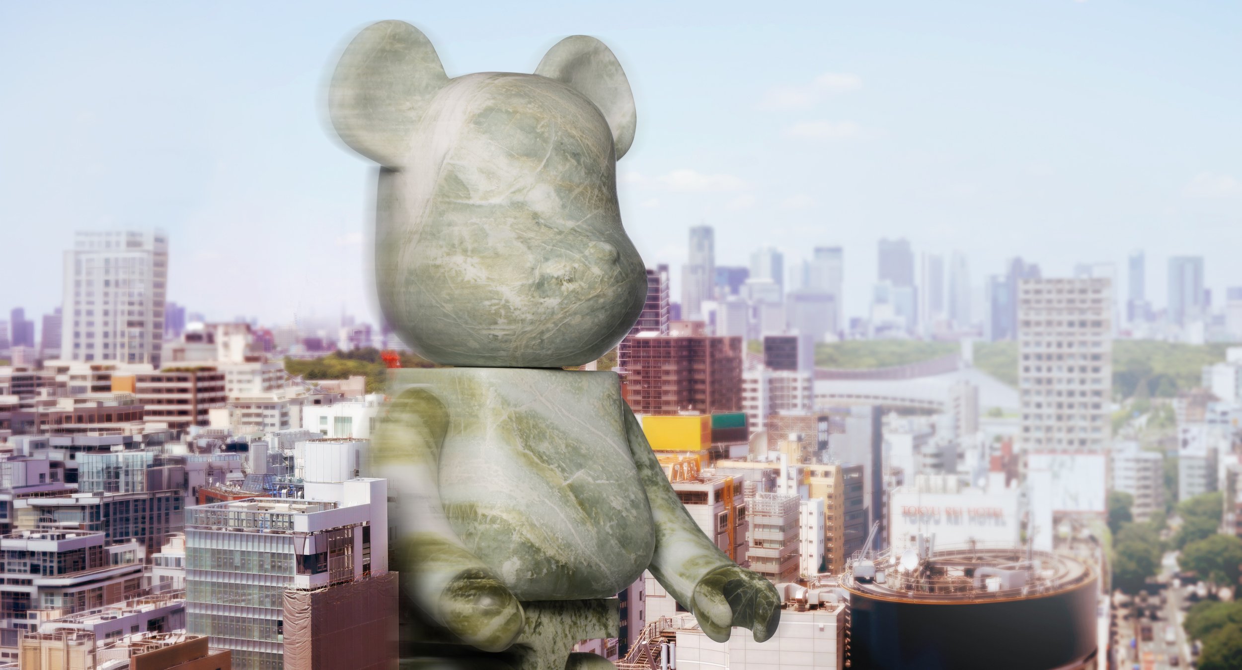 Eine große Statue eines sitzenden Affen auf einer Plattform vor einer Stadt mit Hochhäusern bei Tag.