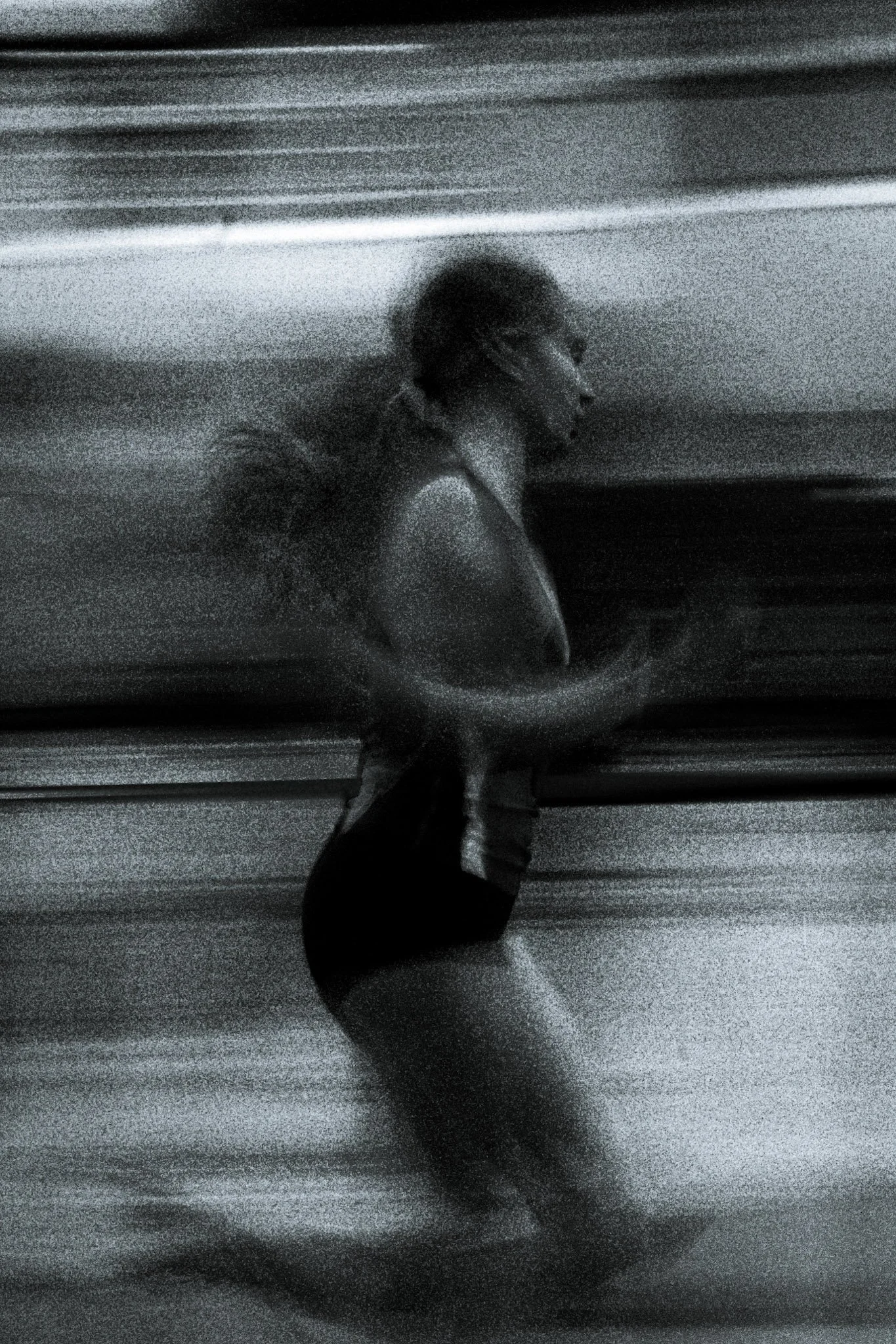 A woman running, captured in motion with a blurred background in black and white.