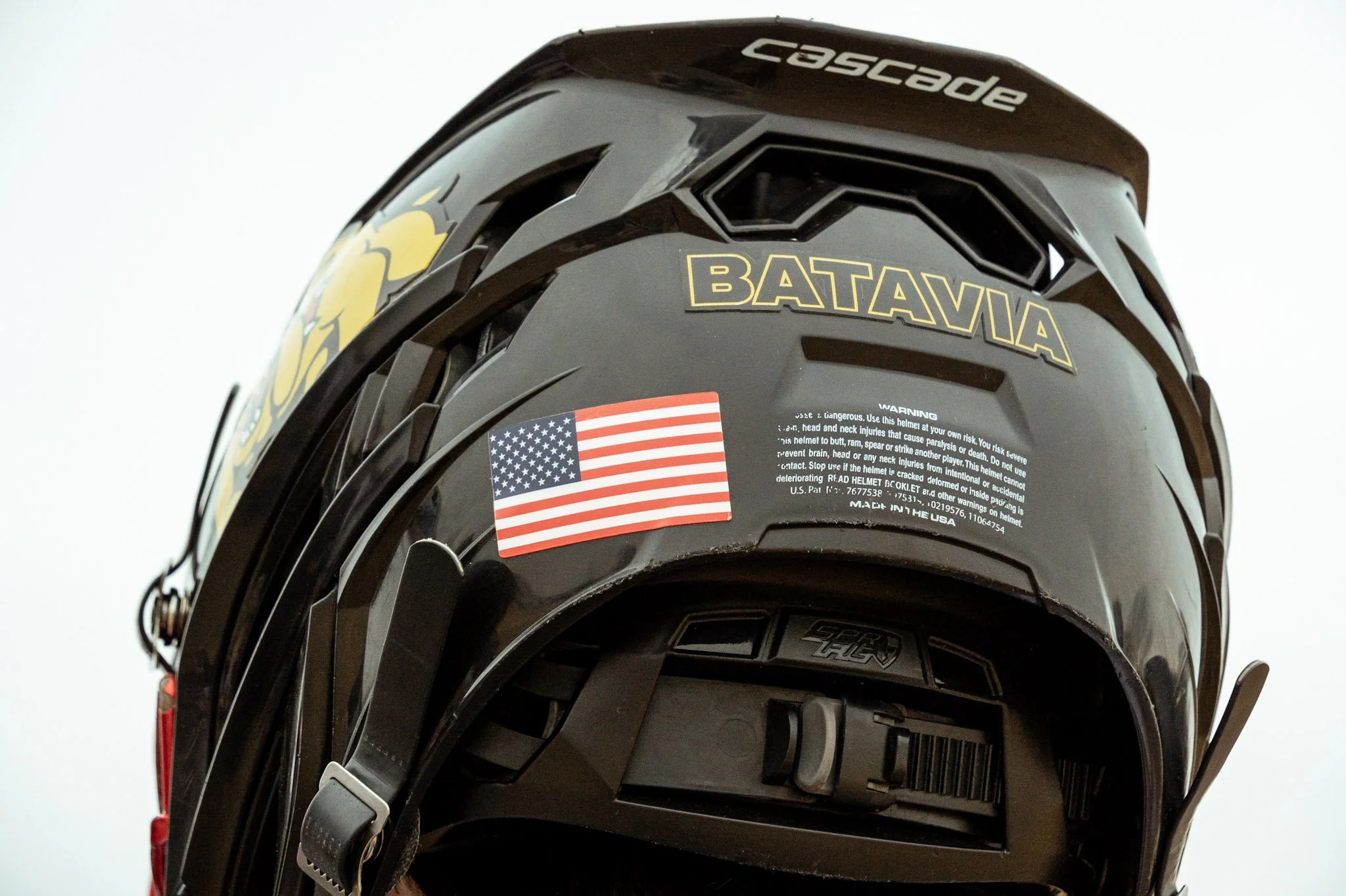 Black motorcycle helmet with a Batavia sticker, American flag sticker, and the brand name 'Cascades' on top.