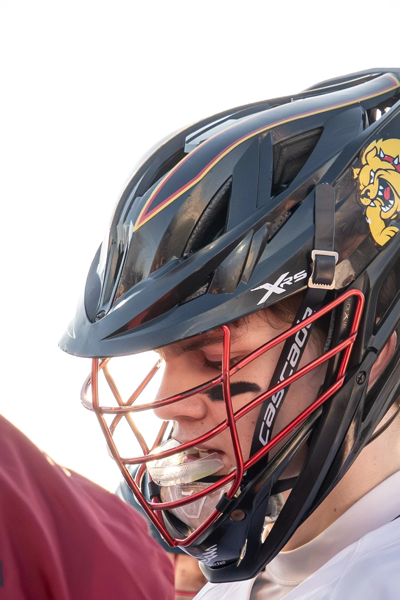 Close-up of a woman wearing a hockey helmet with a lion logo, mouthguard, and sports gear, indicating she is a hockey player.