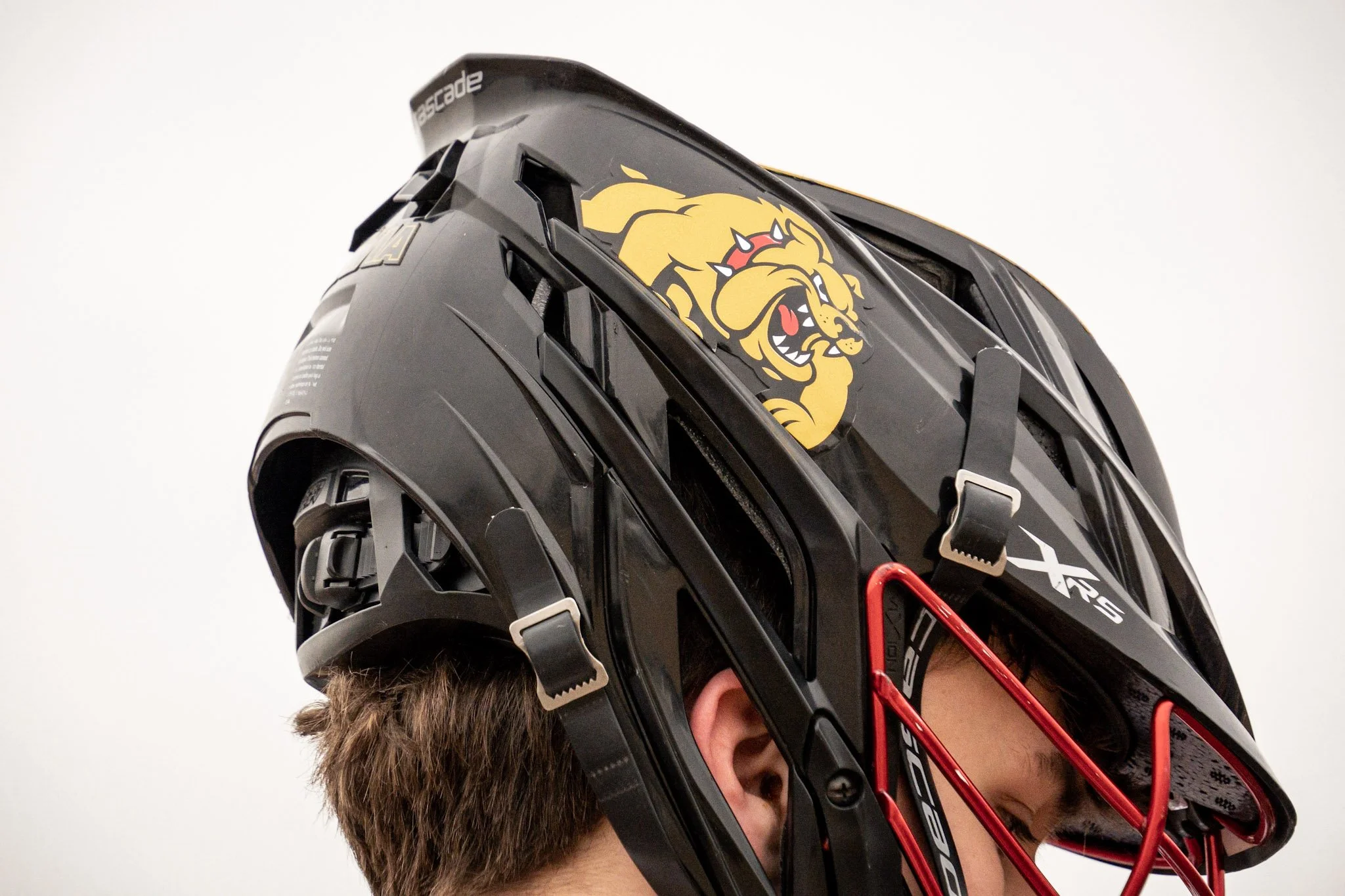 Man wearing a black hockey helmet with a lion logo and red face guard.
