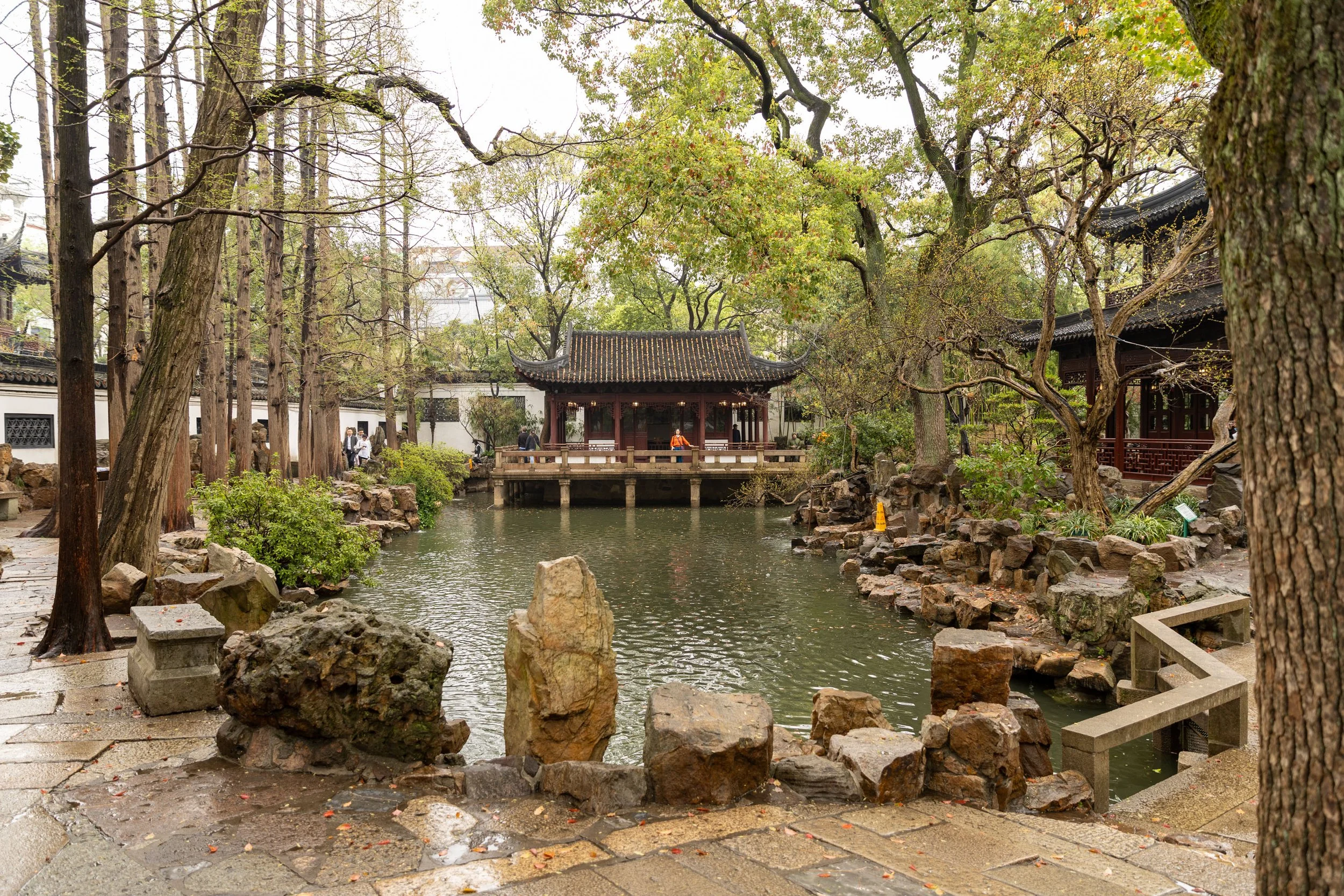Traditional Chinese garden with pond, pavilion, and rock formations.