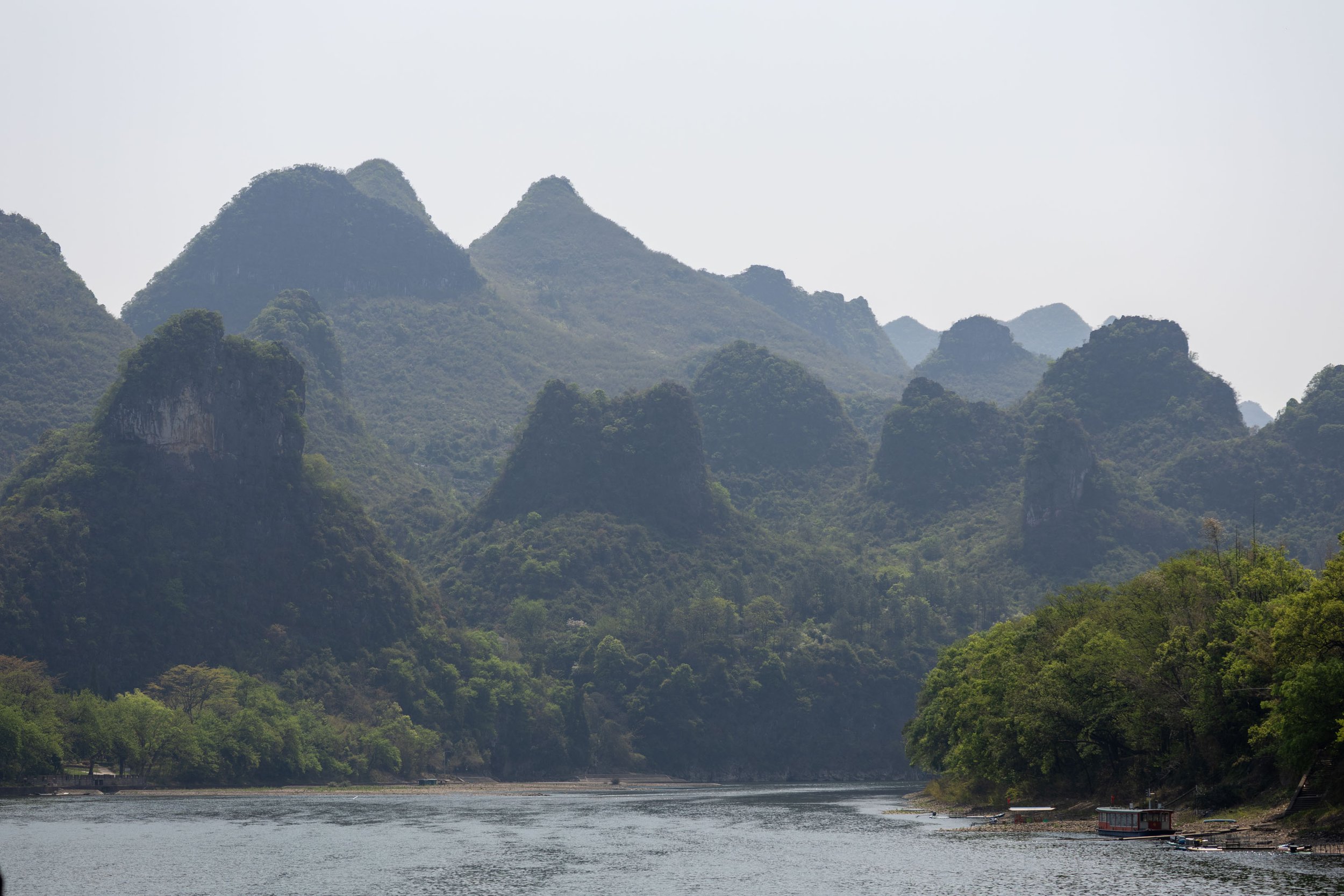 Mountainous landscape with lush green vegetation surrounding a calm river.