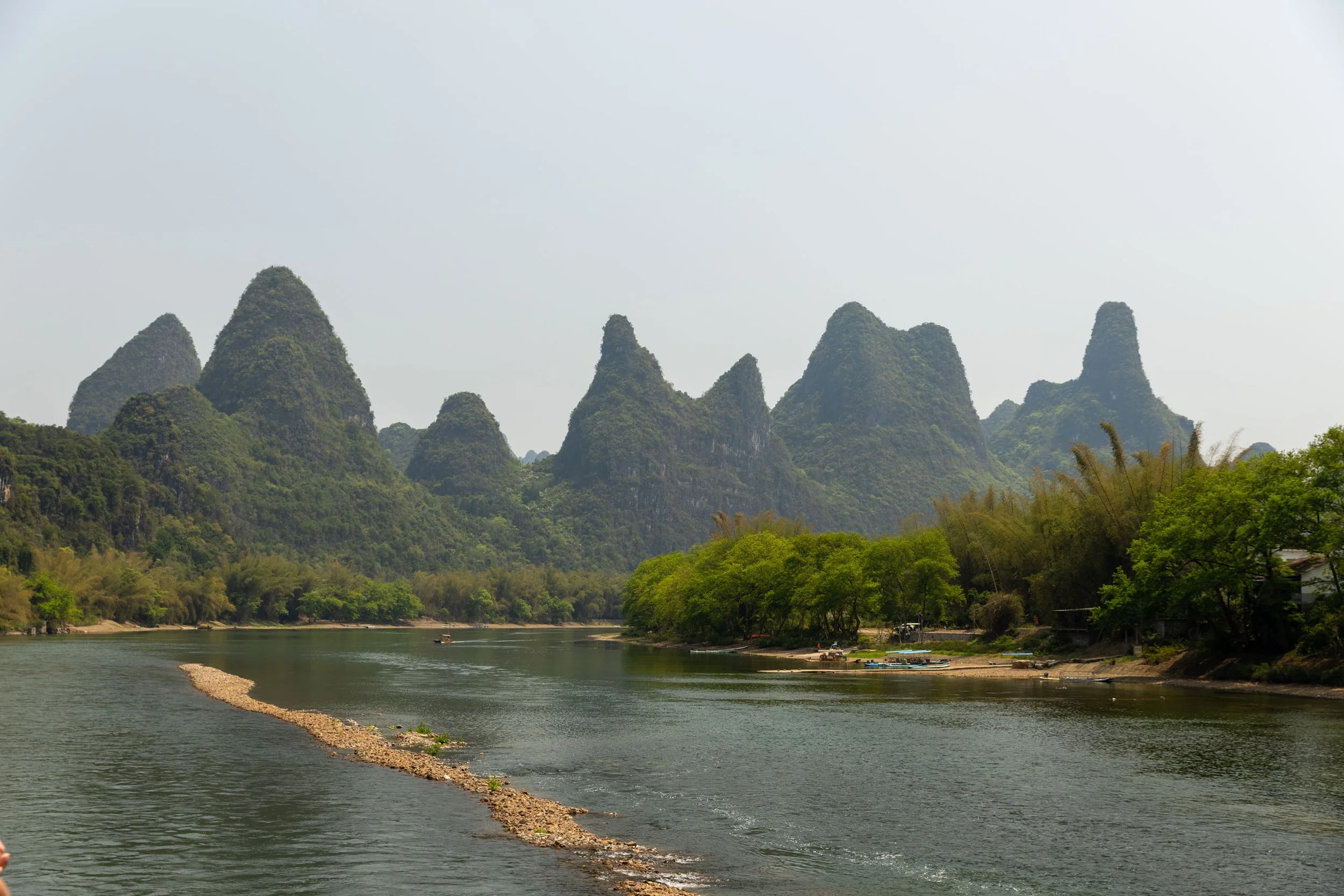 Karst mountains and Li River in Guilin, China, with greenery and a sandy riverbank.