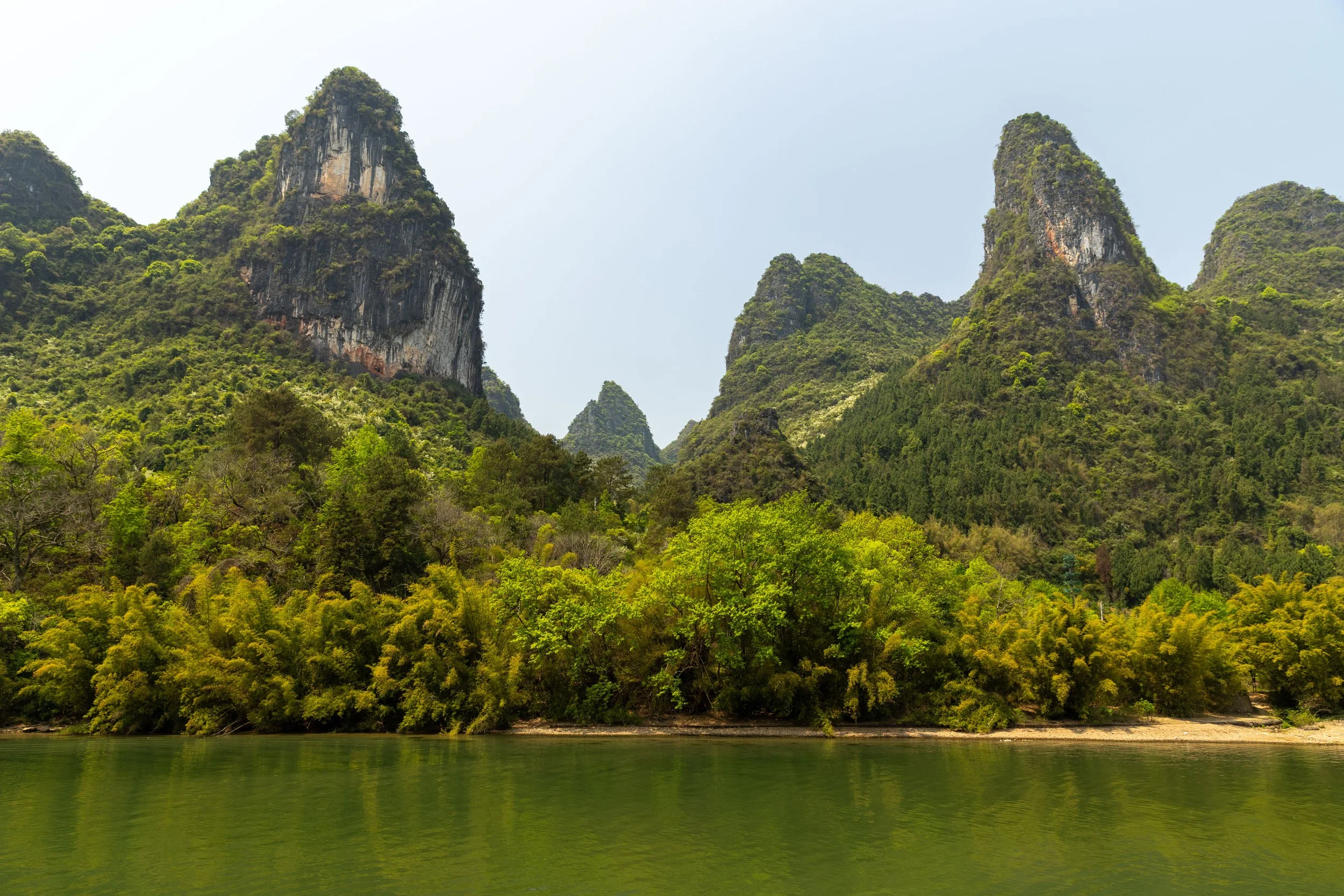 Scenic view of karst mountains and lush greenery reflected in a calm river.