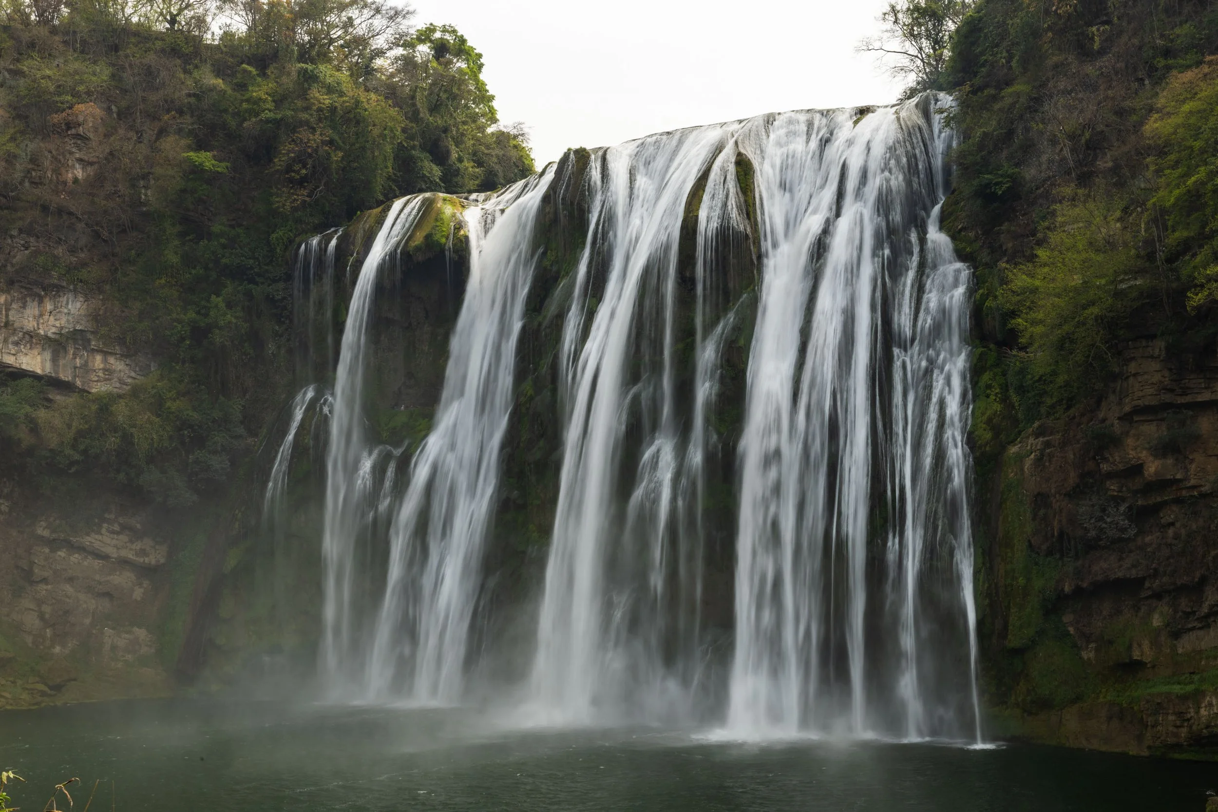 Scenic waterfall cascading over rocky cliffs with lush greenery.