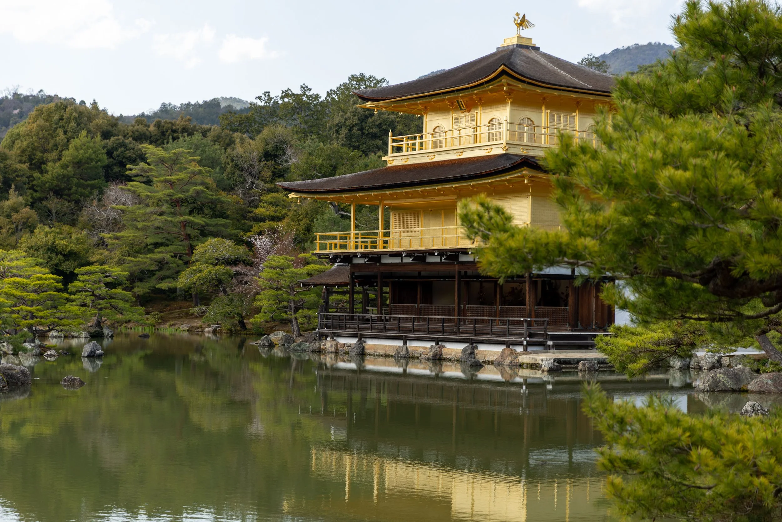 Kinkaku-ji, the Golden Pavilion, in Kyoto, Japan, surrounded by a pond and lush greenery.