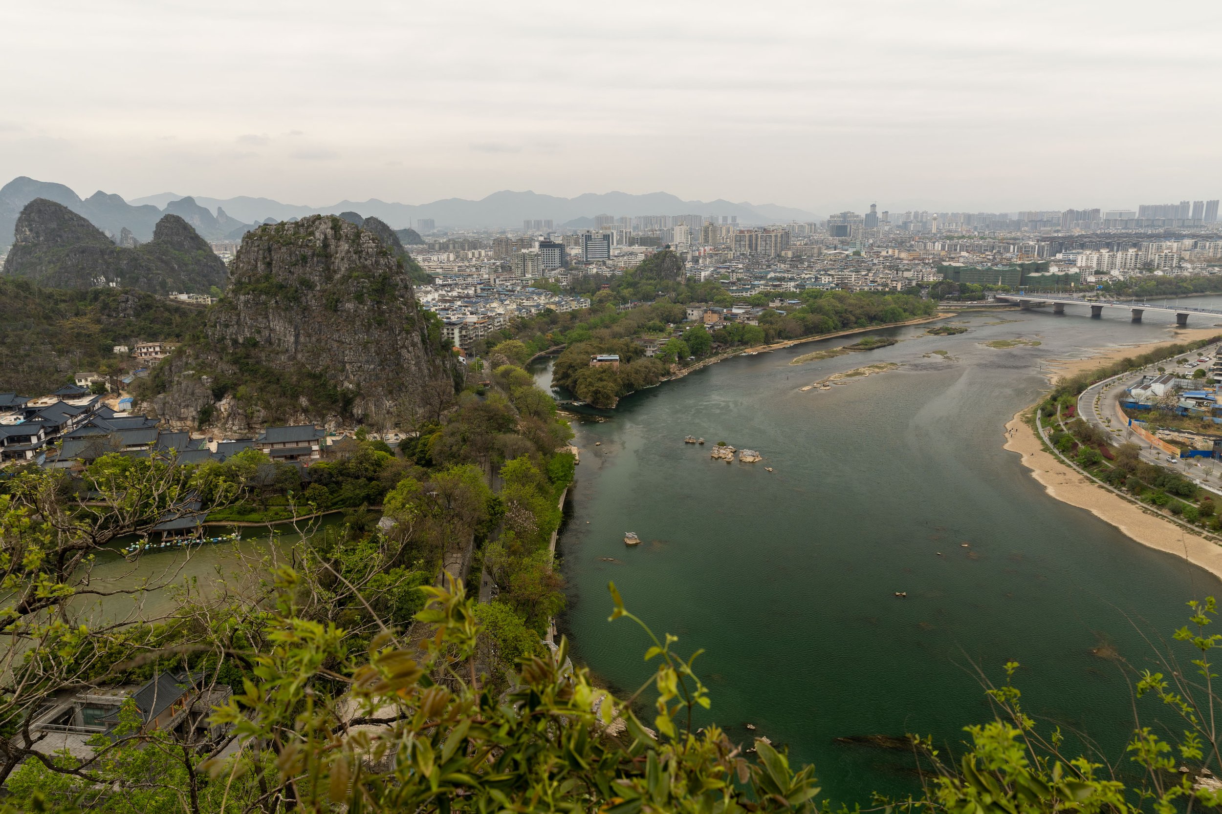 View of Guilin, China, featuring karst mountains, a river, and city buildings.