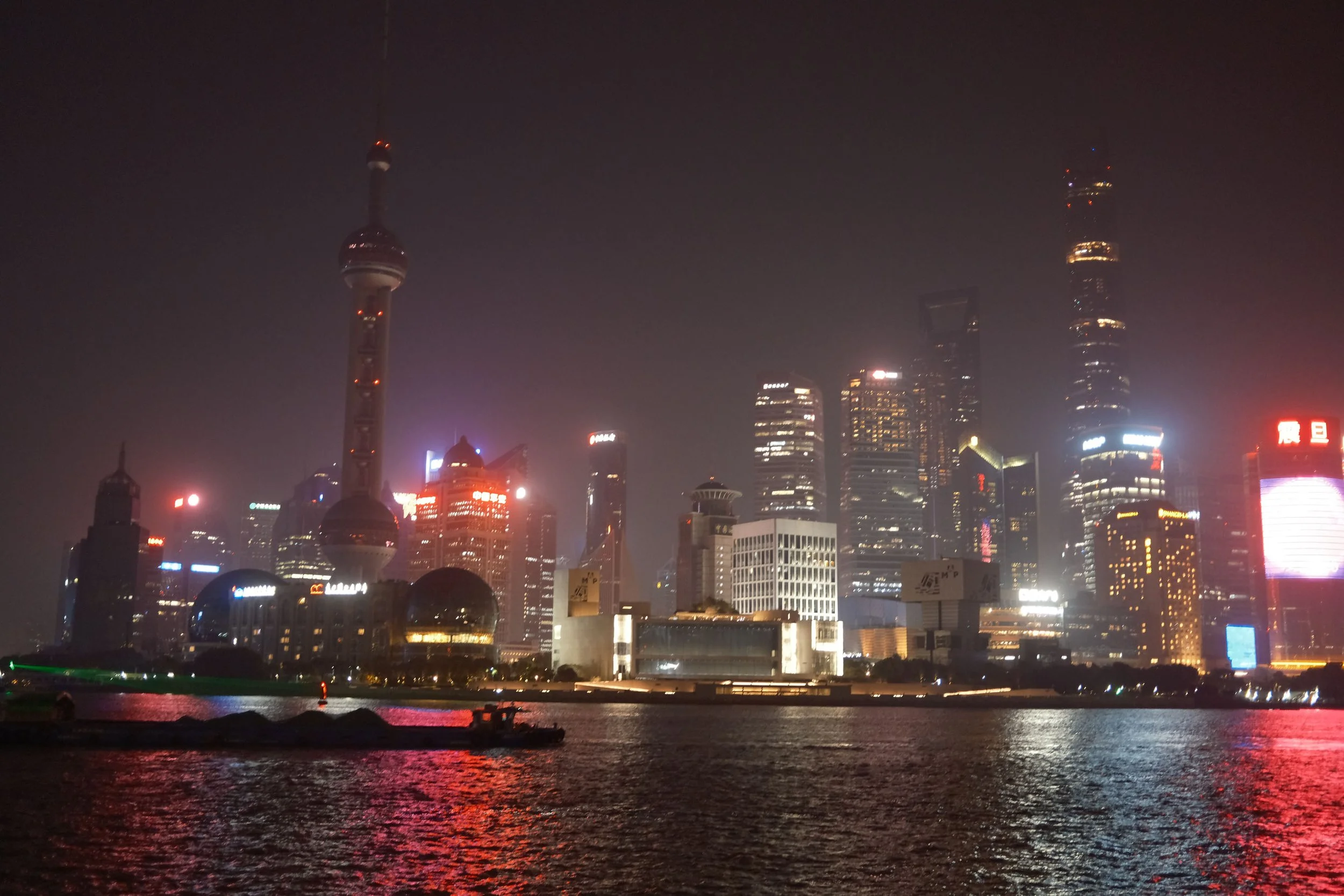 Shanghai skyline at night featuring the Oriental Pearl Tower and illuminated skyscrapers.