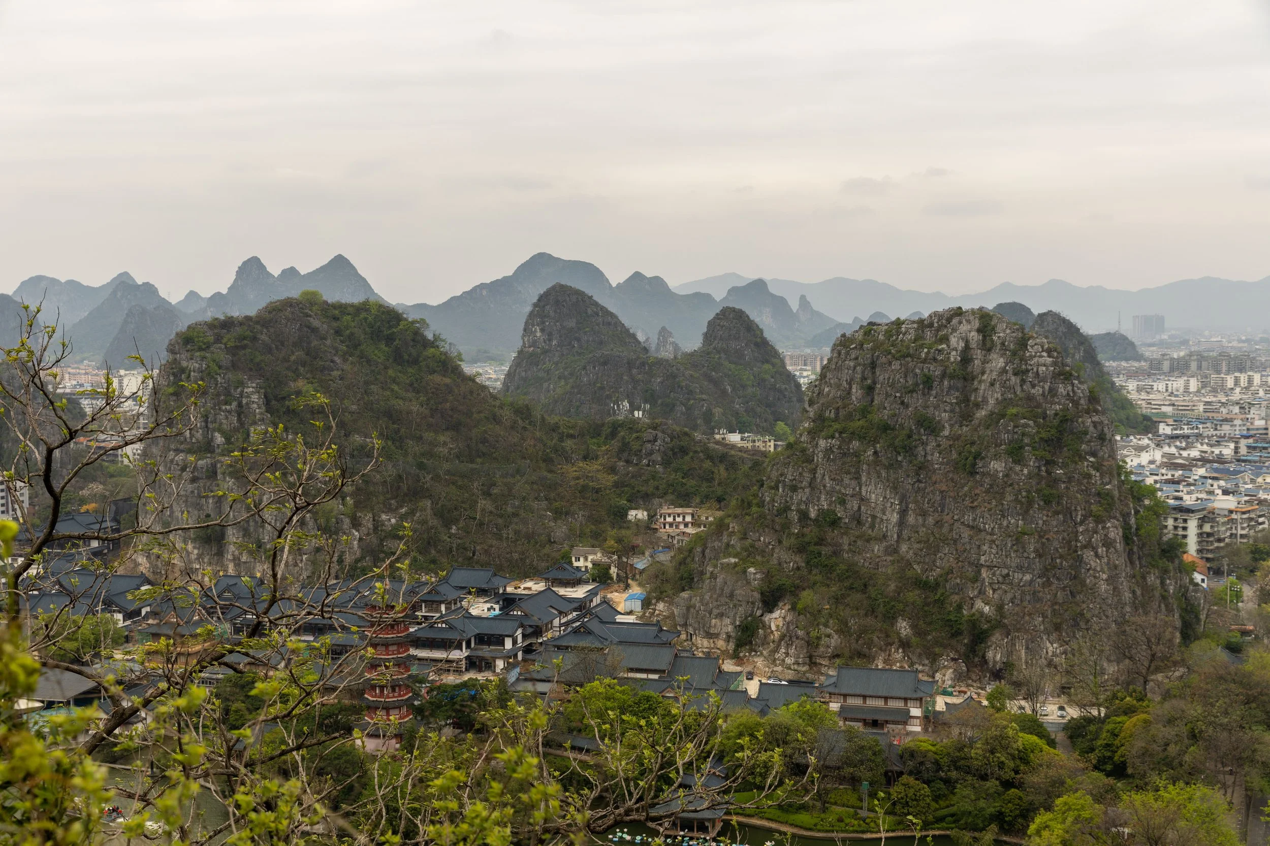 Scenic view of karst mountains and buildings in Guilin, China, with lush greenery and a pagoda.