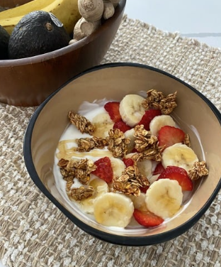 a bowl of yogurt with strawberries bananas and granola