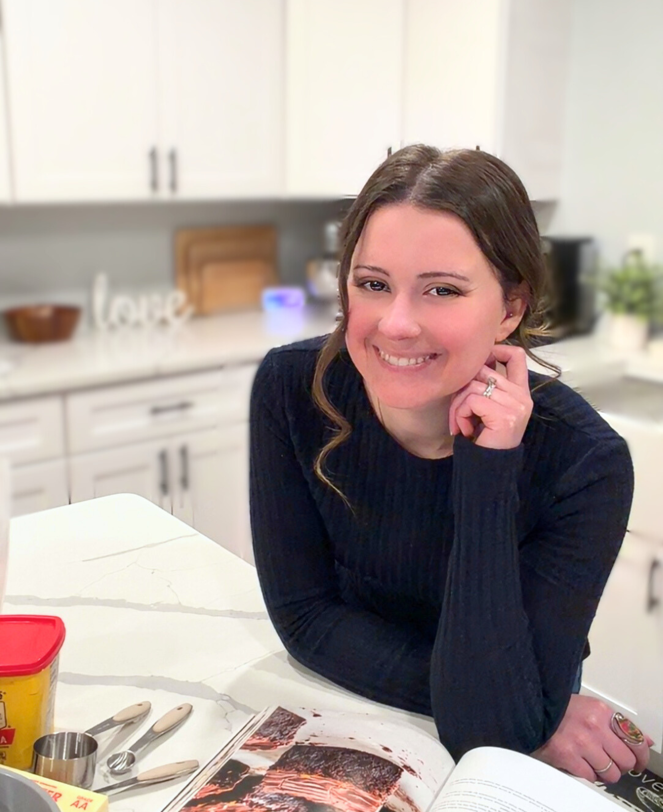 friendly woman in kitchen leaning on counter with a navy shirt