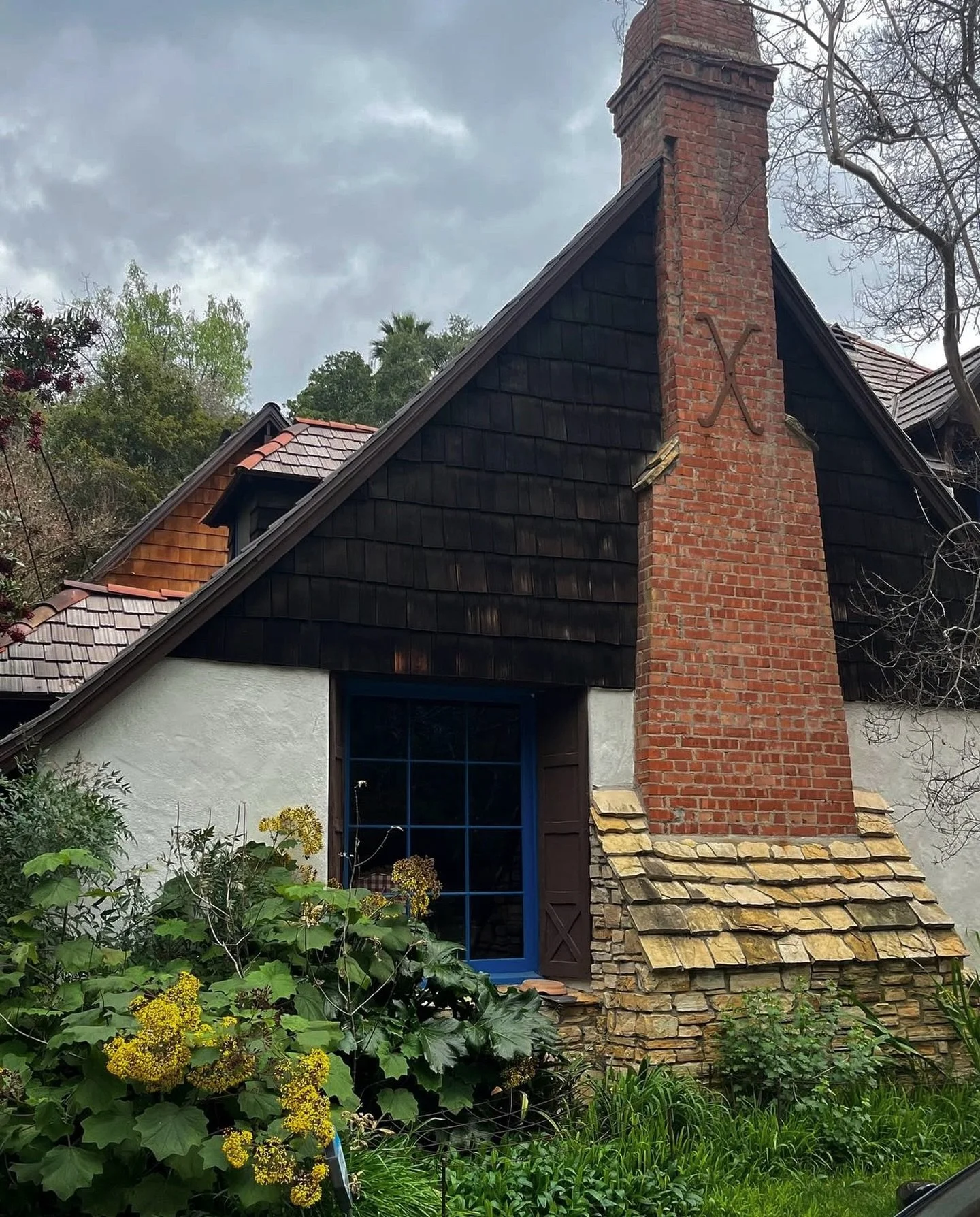 Texture &amp; color, I love this house 

Clay tiles on weathered shake, brick &amp; cast iron on stone, stained cedar &amp; stucco, ultramarine blue &amp; original single pane windows. 

This depth and history is what gives a home true curb stop, and