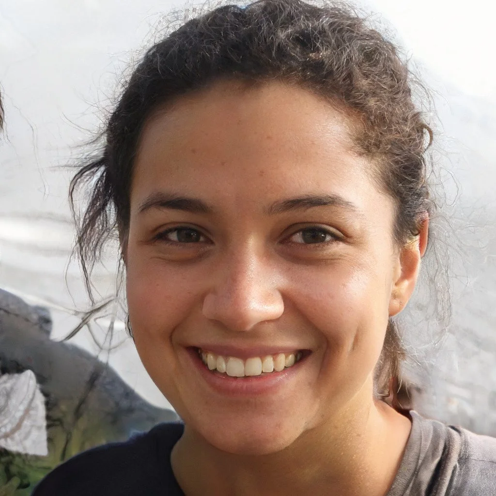 Close-up of a young woman with curly hair smiling outdoors near a body of water.