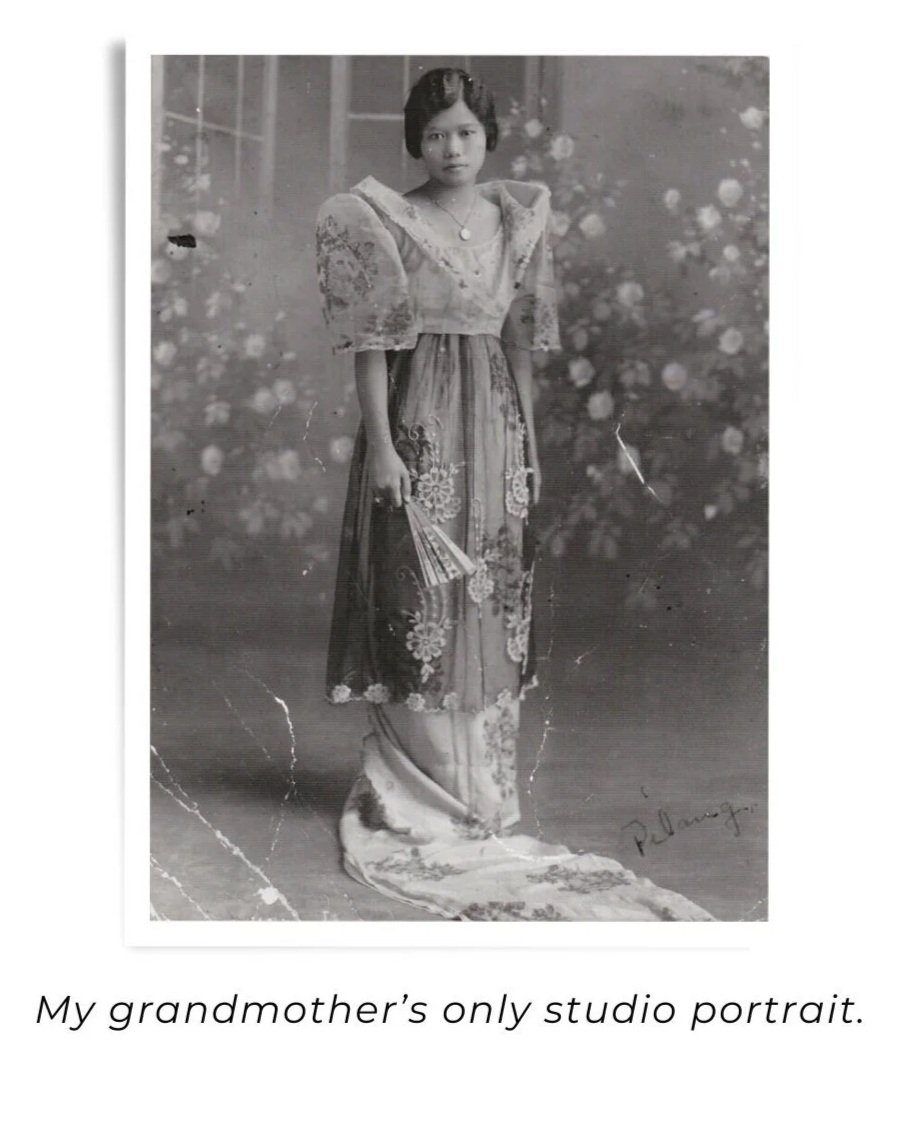 Black and white portrait of a woman in traditional dress holding a fan, standing against a floral backdrop.