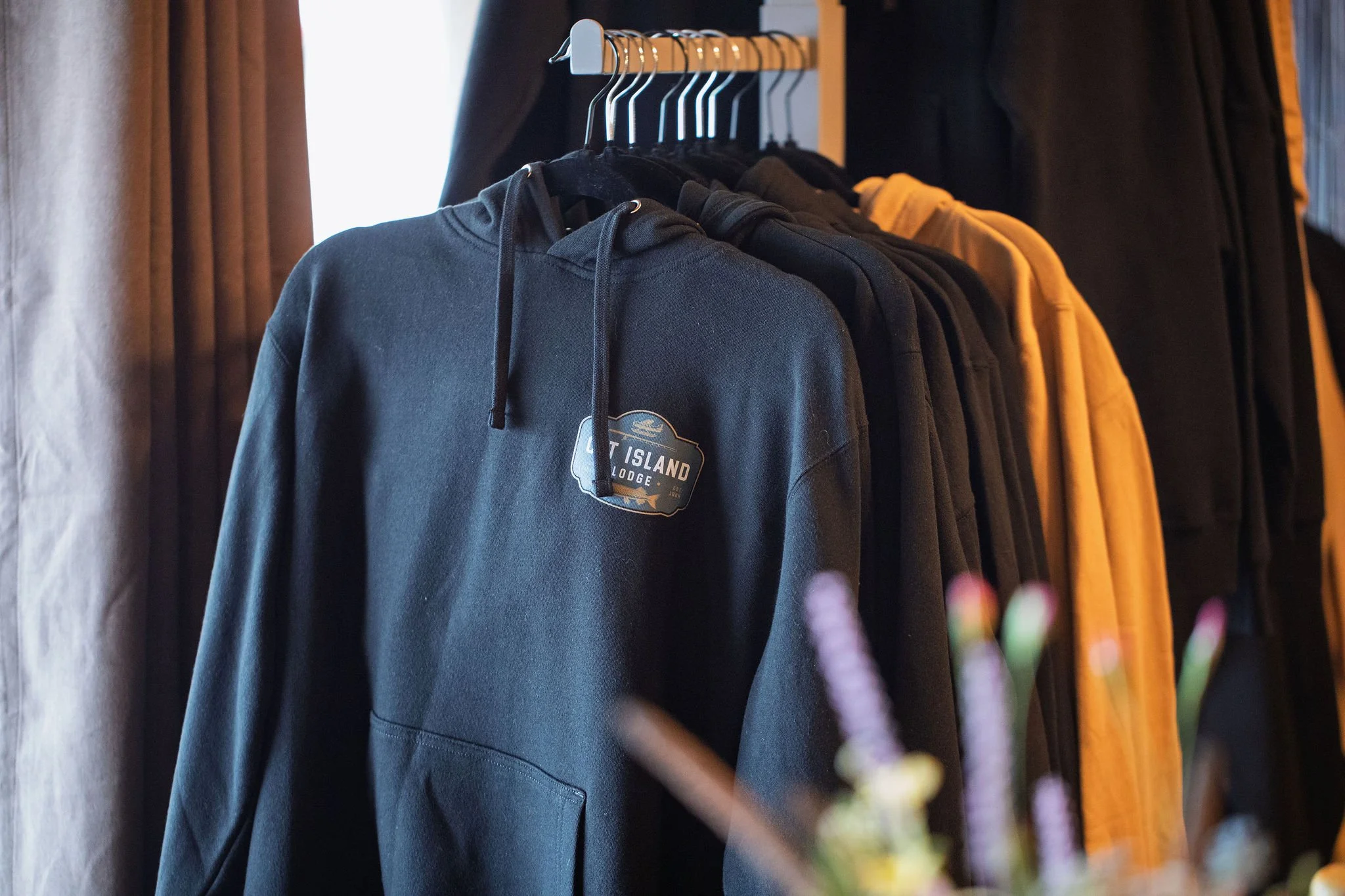 A clothing rack with hoodies and sweatshirts in black and yellow hanging on hangers.