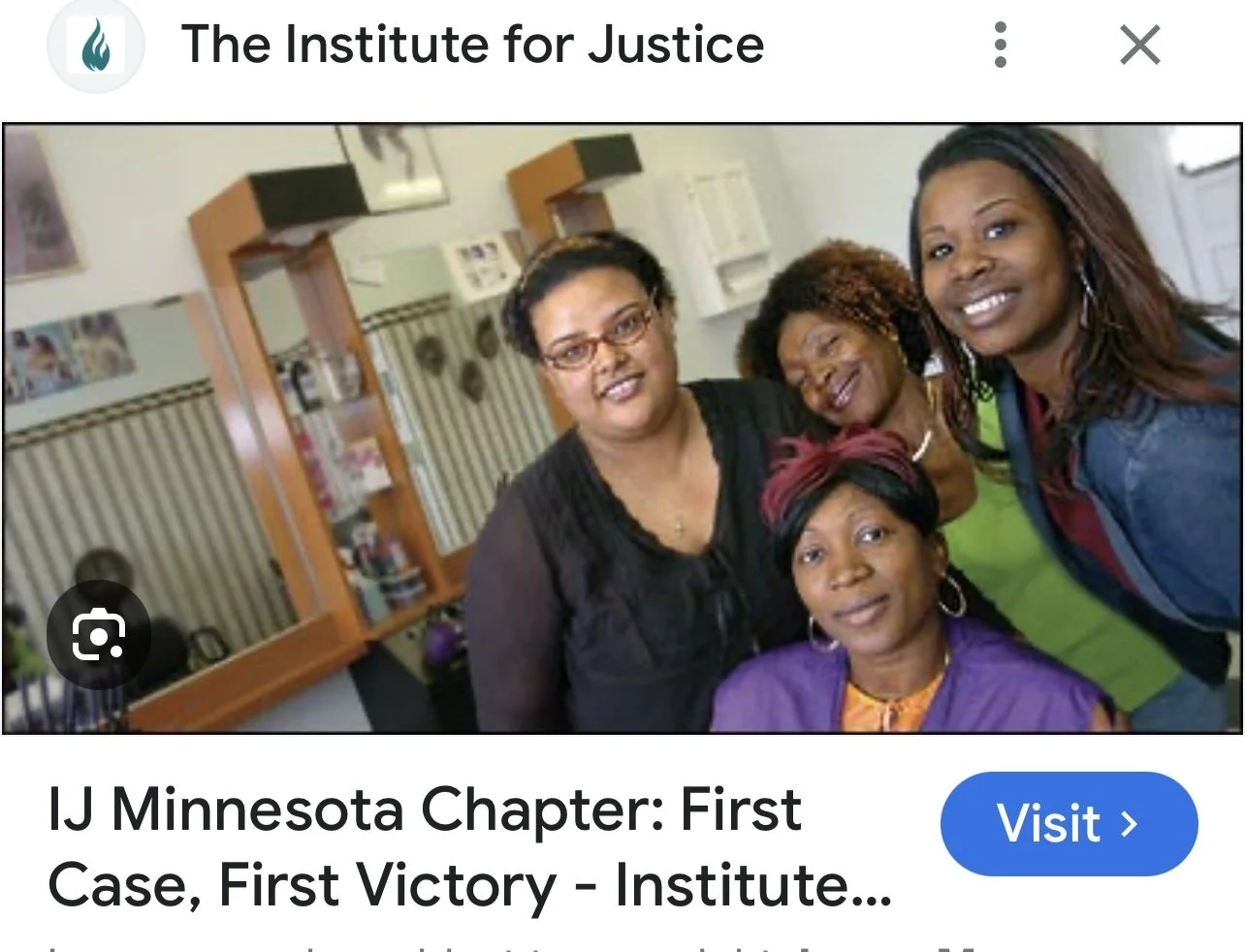 Five women of diverse African American backgrounds smiling and posing together inside an office or community space.