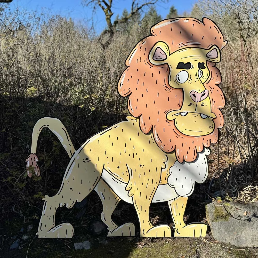Cartoon lion cutout in a grassy outdoor setting with a blue sky background.