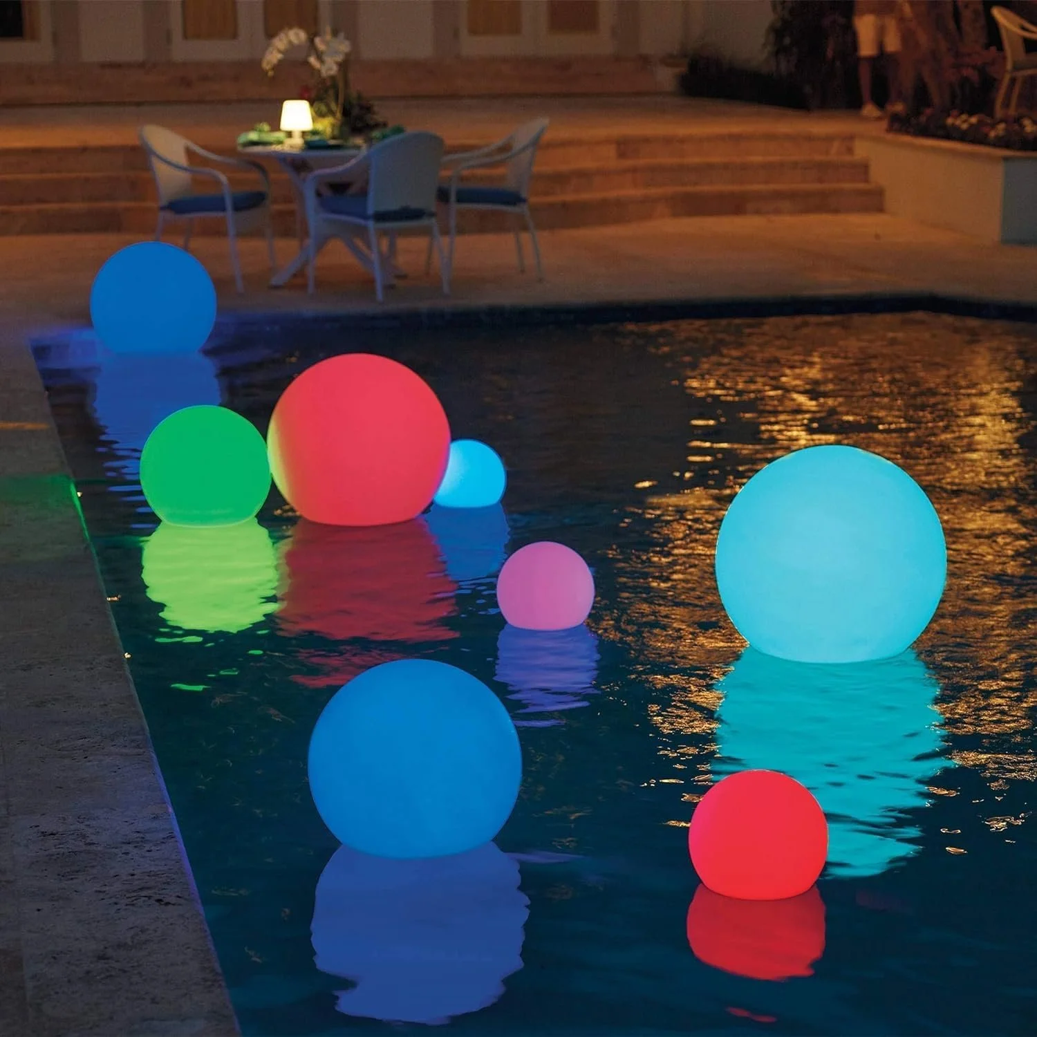 Glowing multicolored spheres floating on water at night.