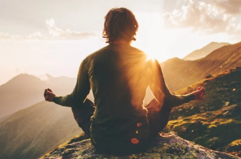 A person practicing yoga on a mountain top at sunrise