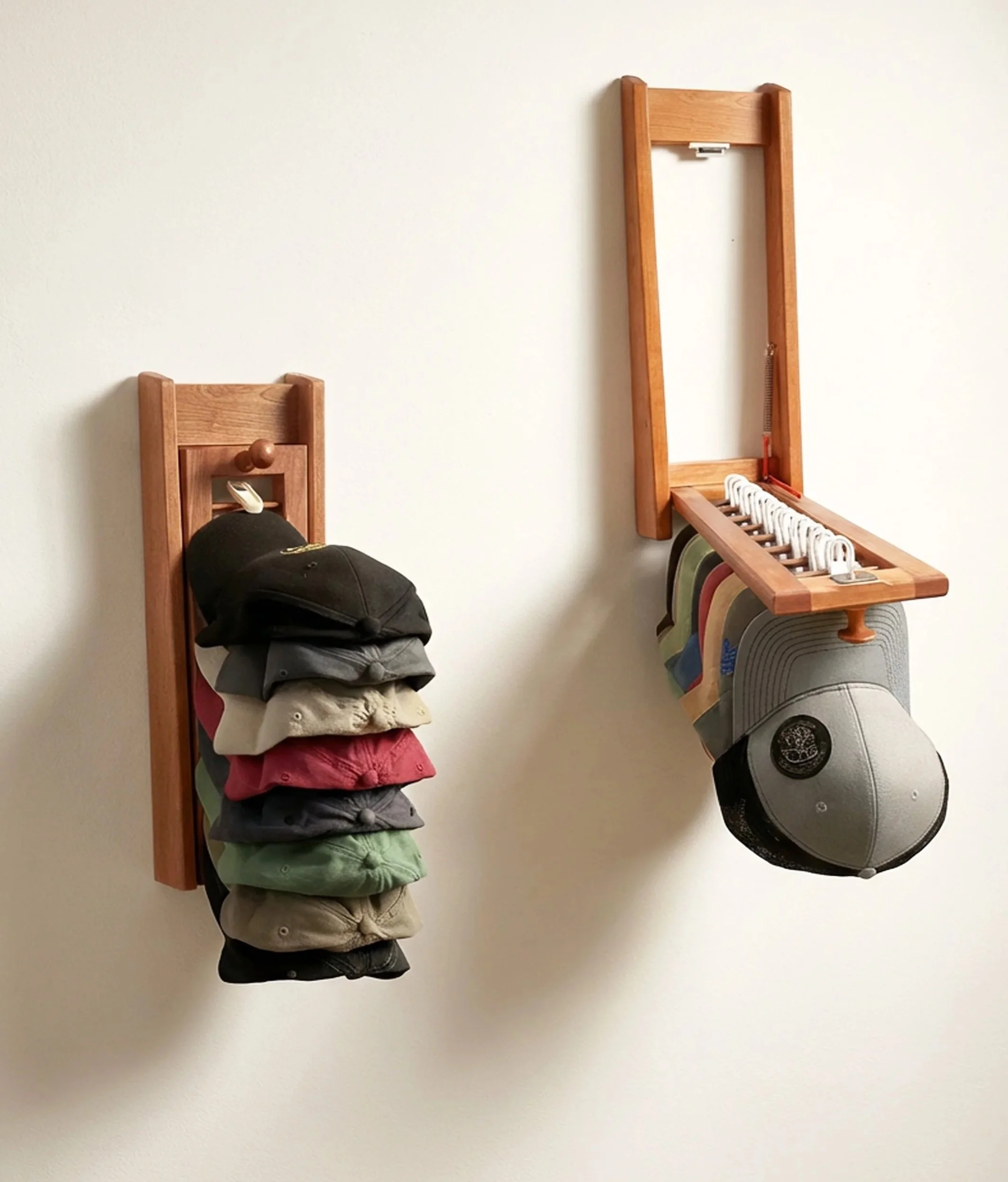 Two wall-mounted hat racks, one with several baseball caps of different colors hanging on it, and the other with caps and hats stored using hooks.
