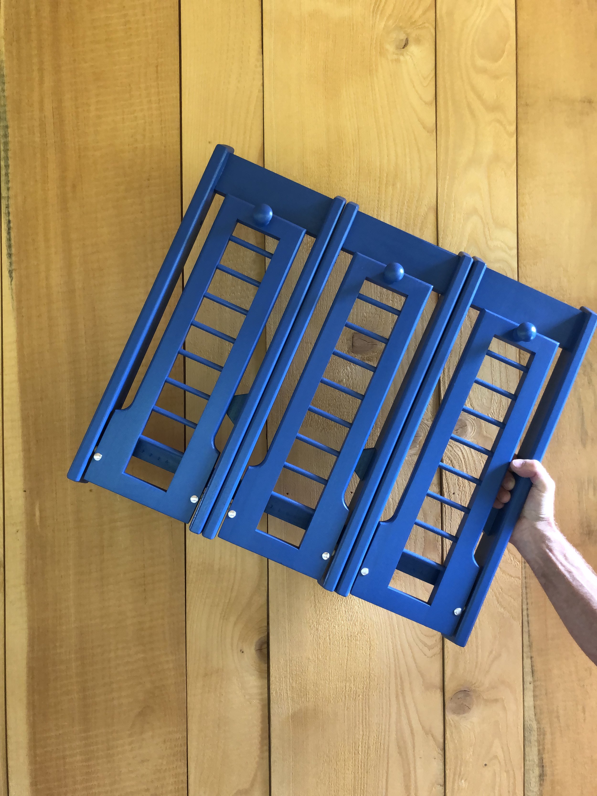 Person holding a blue wooden foldable chair.