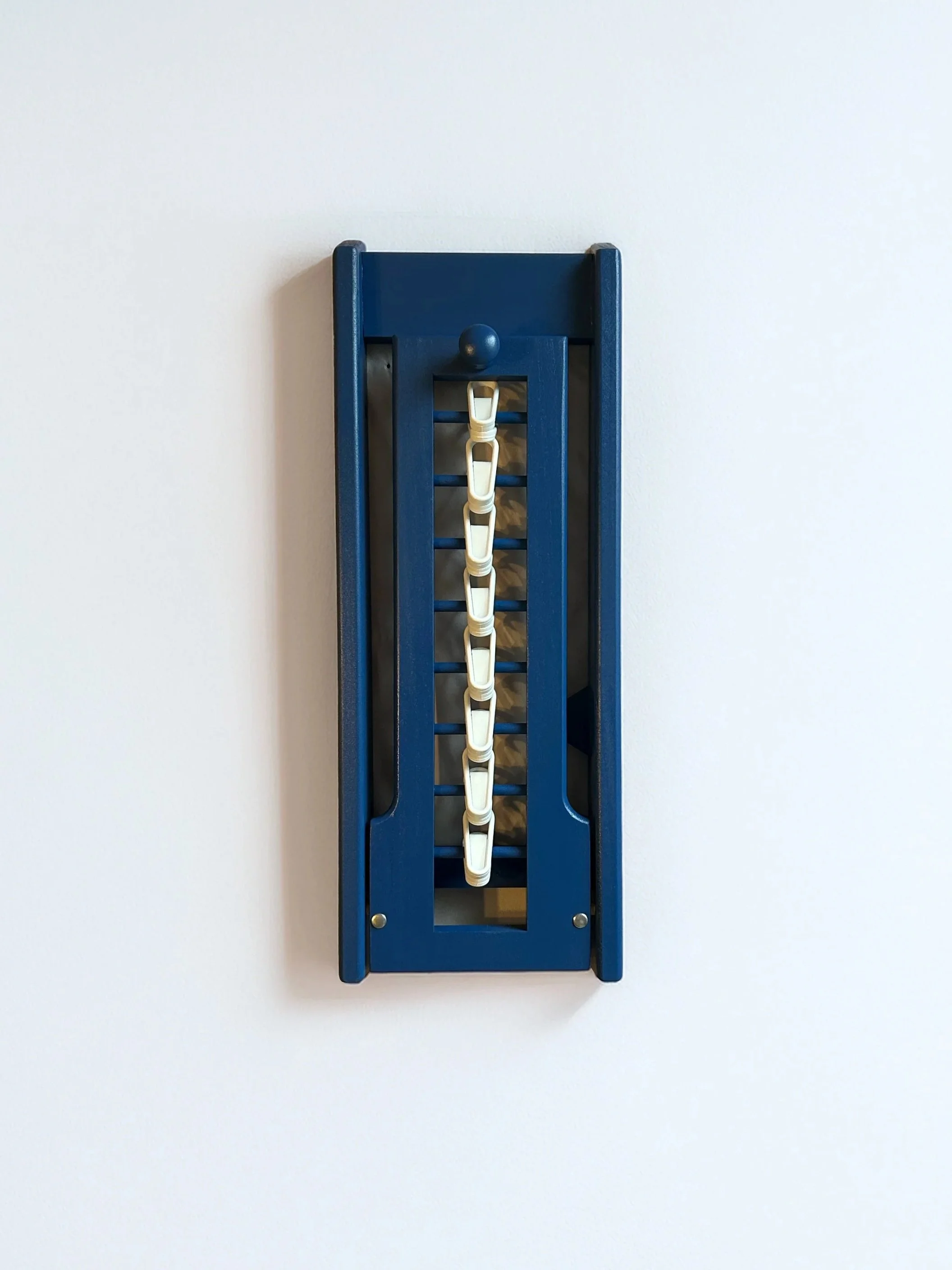 Blue plastic wand holder with white wands hanging on a white wall.