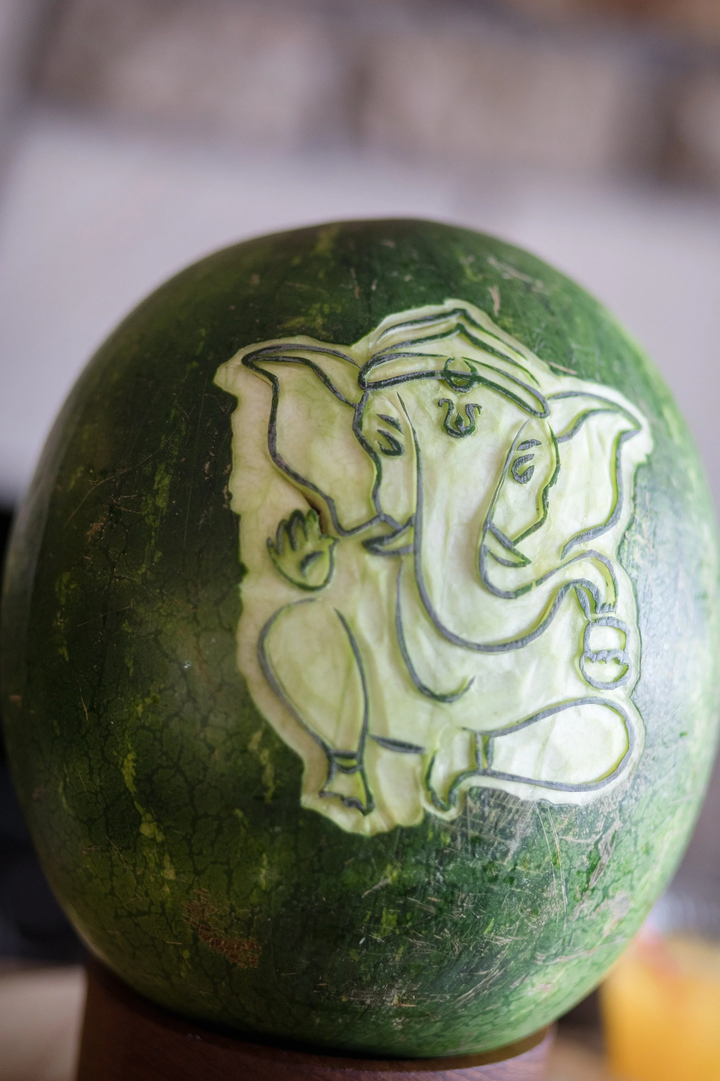 Watermelon carved to resemble Lord Ganesha, an elephant-headed Hindu deity, with detailed outlines of the face, trunk, ears, and a hand gesture.
