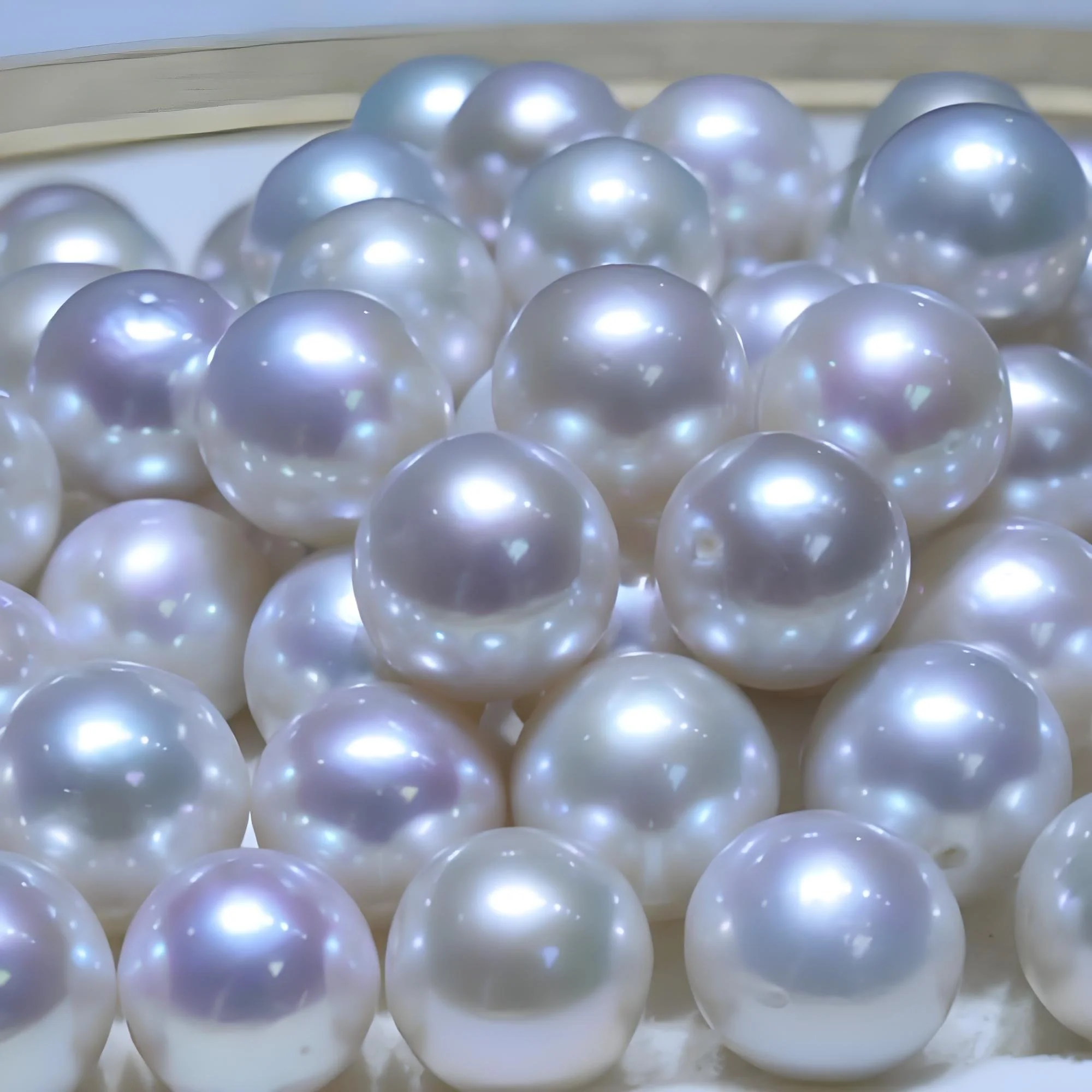 An exquisite close-up of a cluster of high-quality, lustrous natural pearls with iridescent pink and silvery-white overtones. This detailed shot captures the refined elegance and organic beauty of Tongbao's heritage pearl collection.