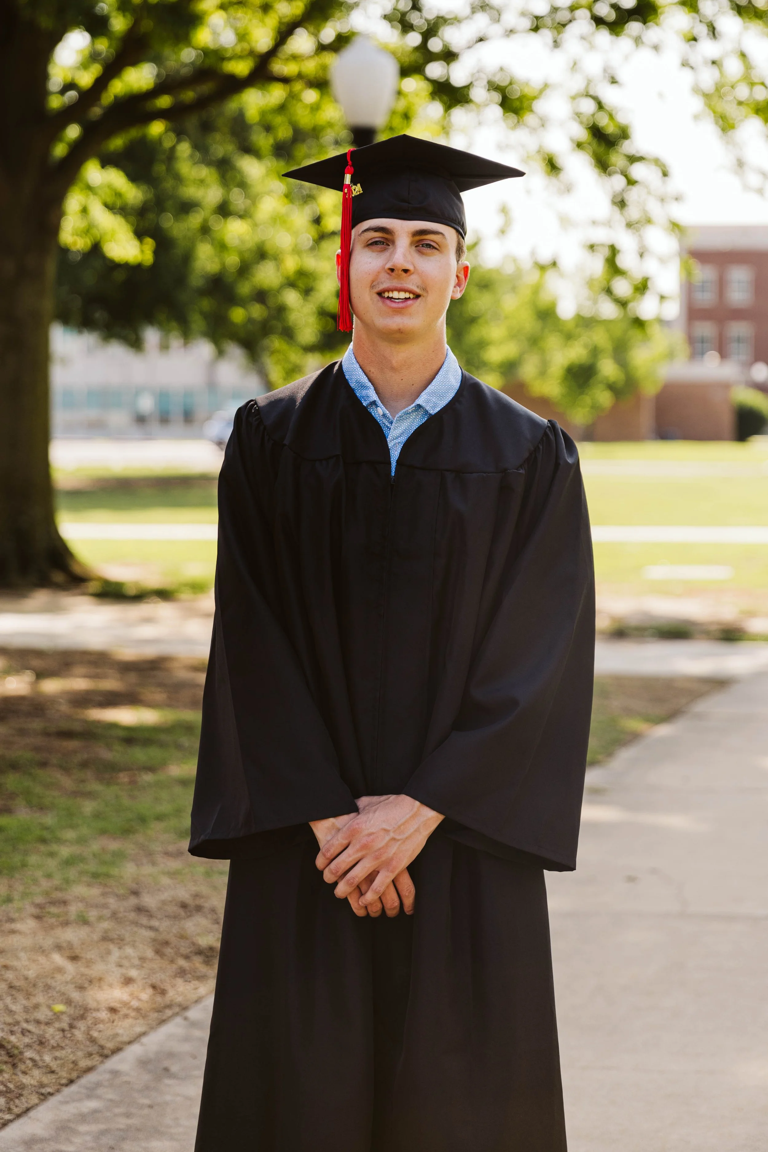Person in graduation cap and gown standing outdoors