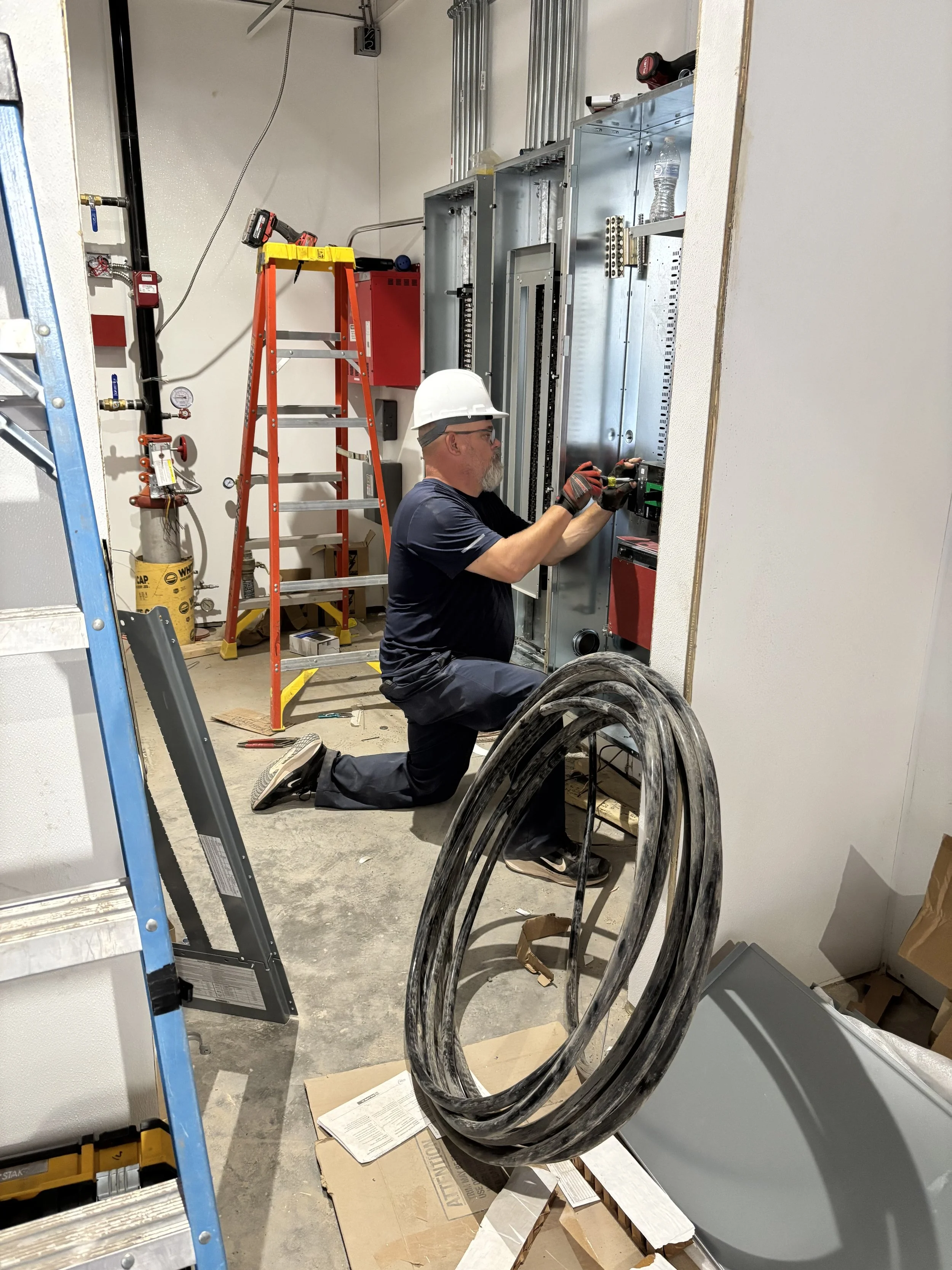 Electrician and owner installing communication and electrical panels during a commercial construction project in Arizona.