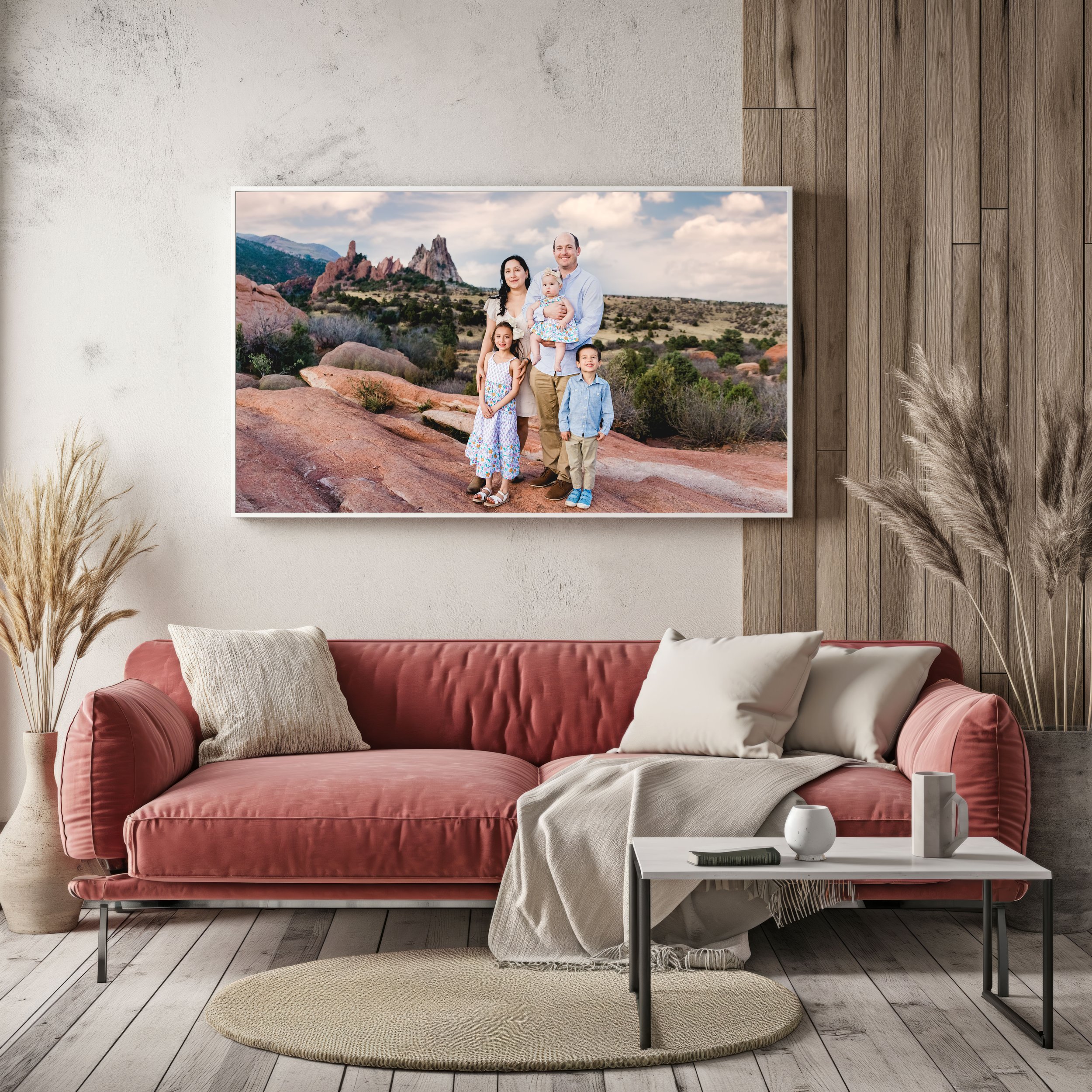 A couple holding hands and walking through a grassy field with mountains in the background, during a cloudy day.