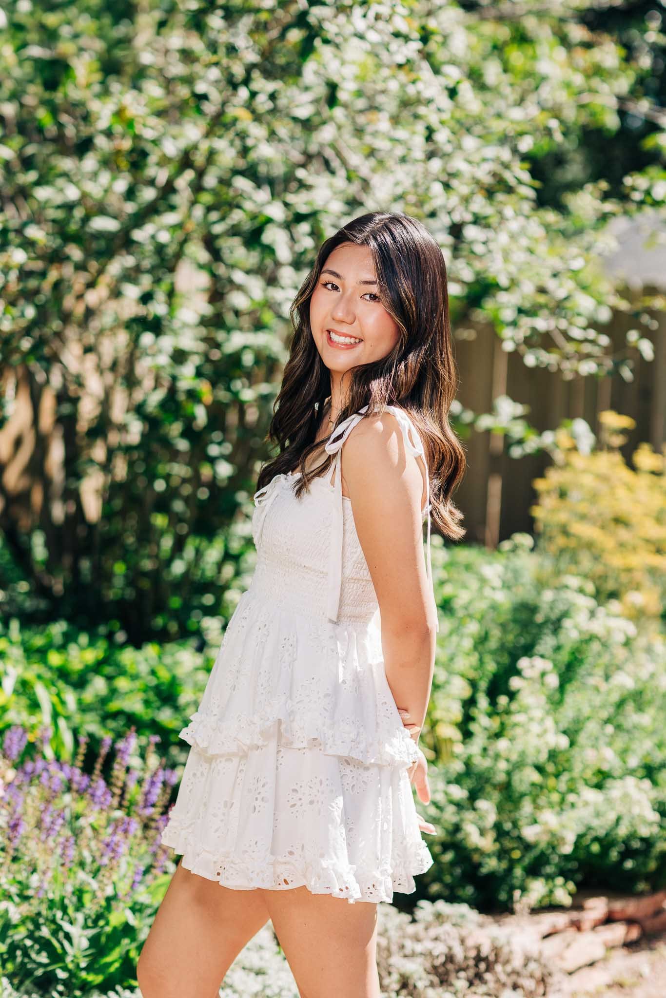 Young woman in white summer dress smiling outdoors in a garden