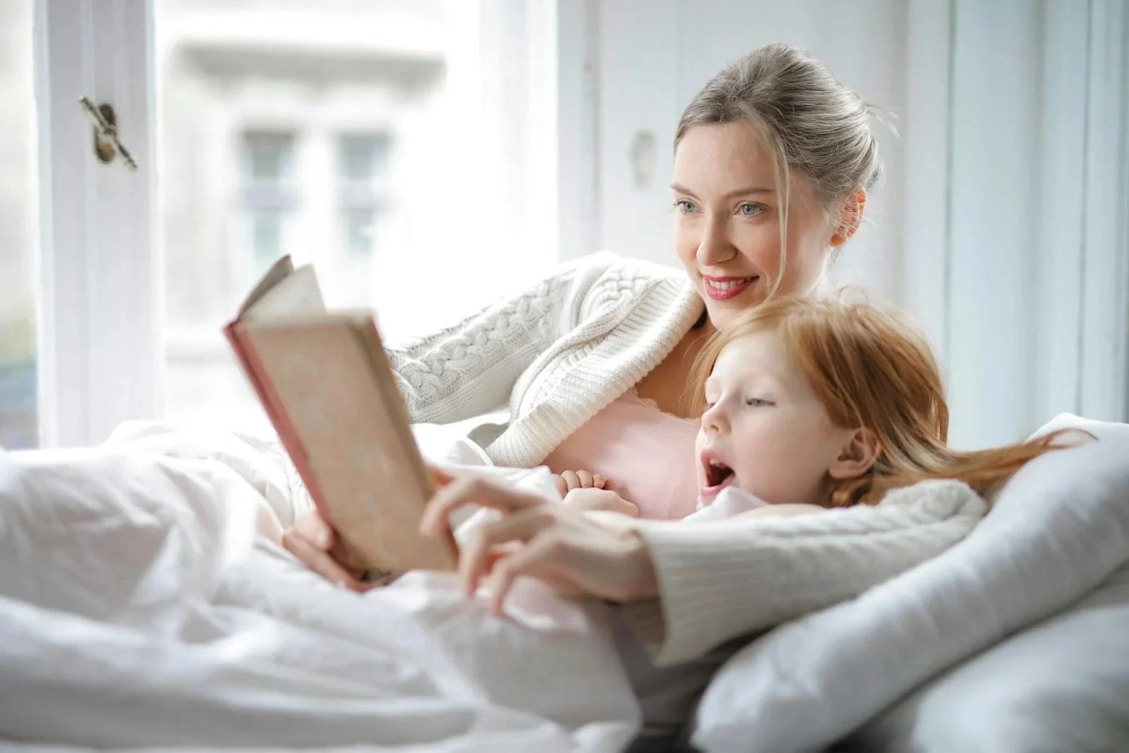 mother-and-daughter-reading-book-with-interest-in-bed-3755514.JPEG