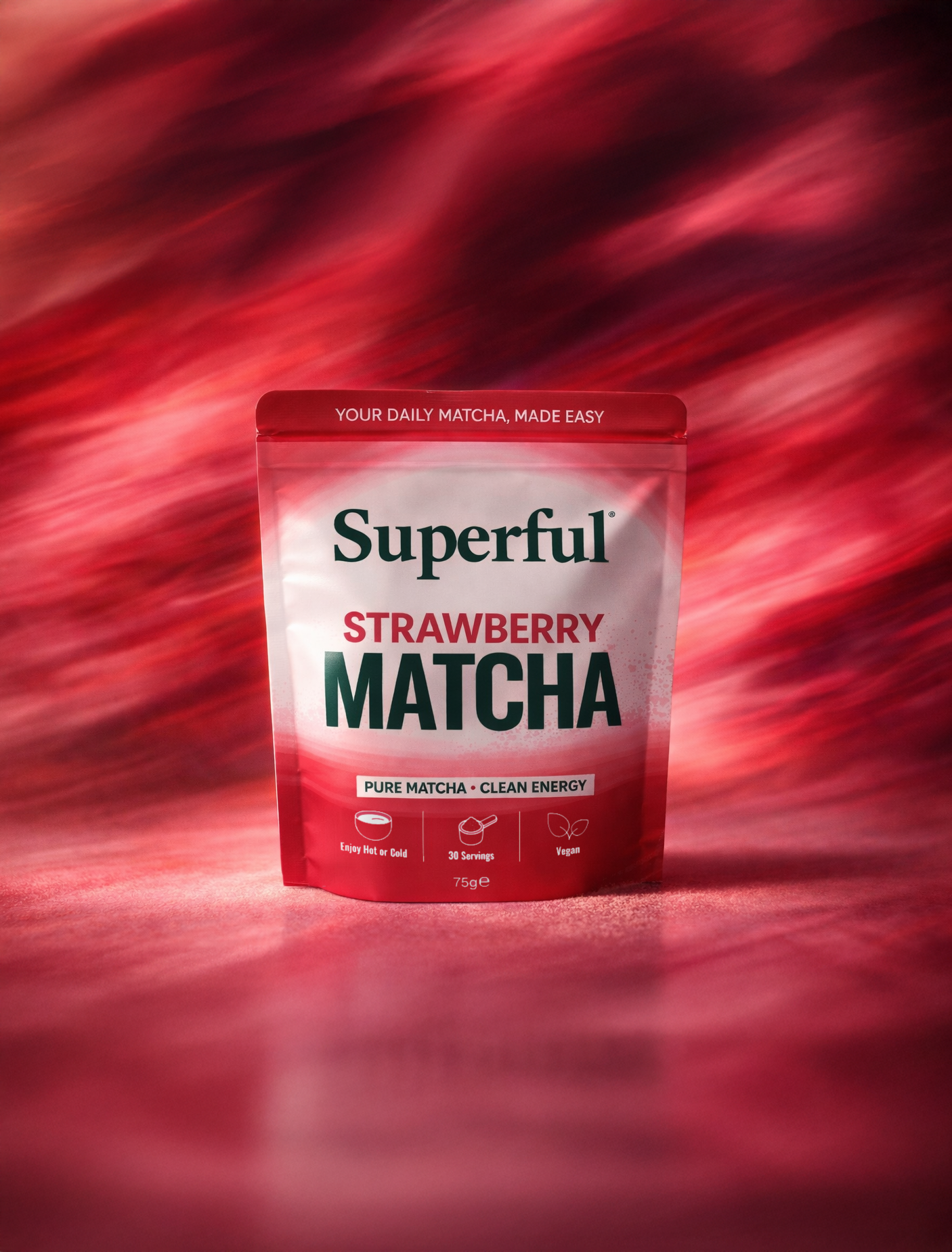 Front-facing Superful Strawberry Matcha pouch displayed against a dynamic abstract red and pink motion-blur background in a premium campaign-style product image.