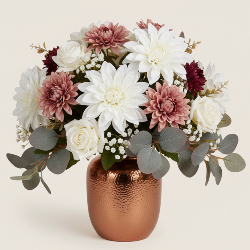 A copper textured vase holding a bouquet of white, pink, and burgundy flowers with eucalyptus leaves.
