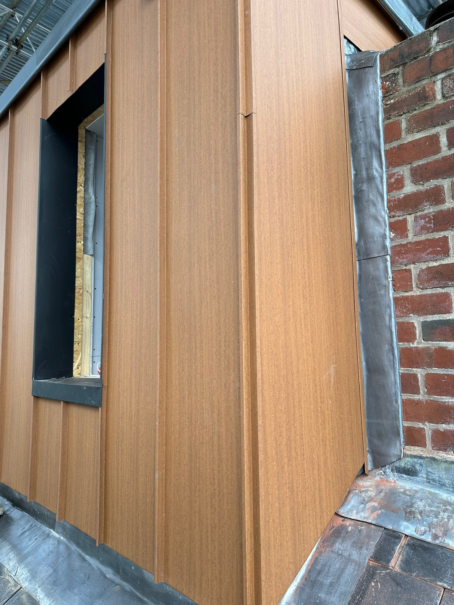 Close-up of a building's exterior with vertical wooden panel siding and adjacent red brick wall.