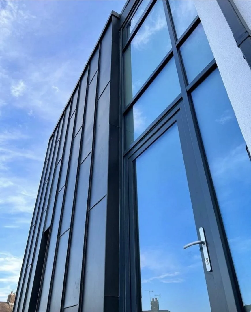 Modern building facade with large glass windows and blue sky reflection