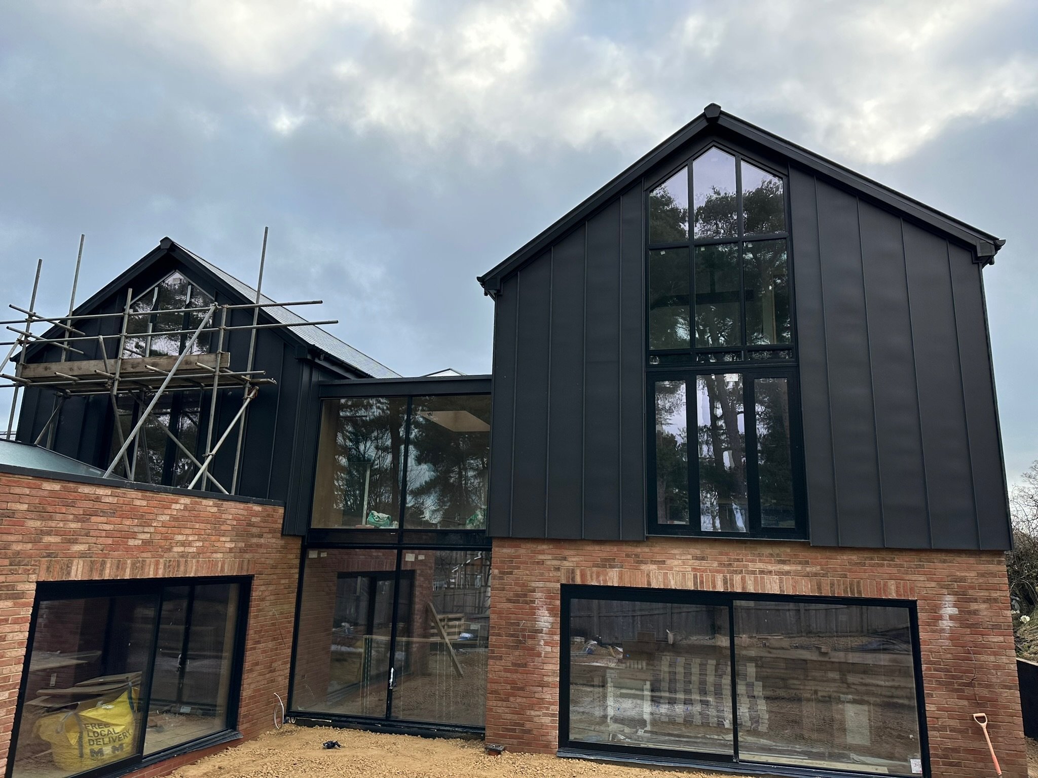 Modern house under construction with dark metal cladding and large windows