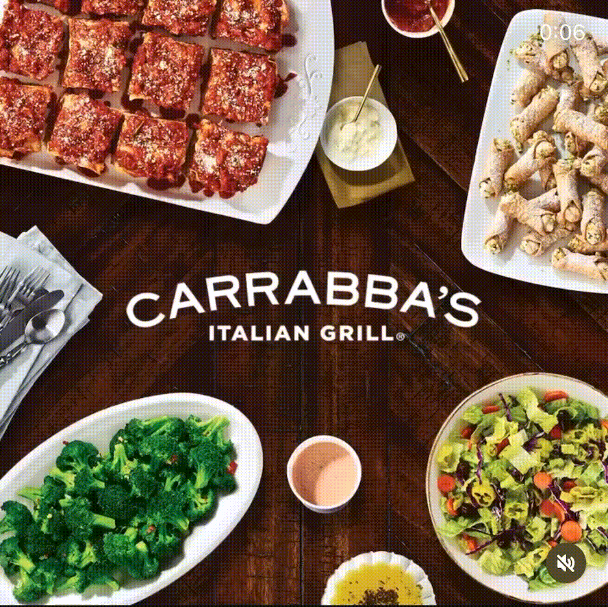 A table with a variety of Italian dishes, including baked chicken wings topped with herbs, a plate of roasted broccoli, a mixed salad, breadsticks, and dipping sauces.