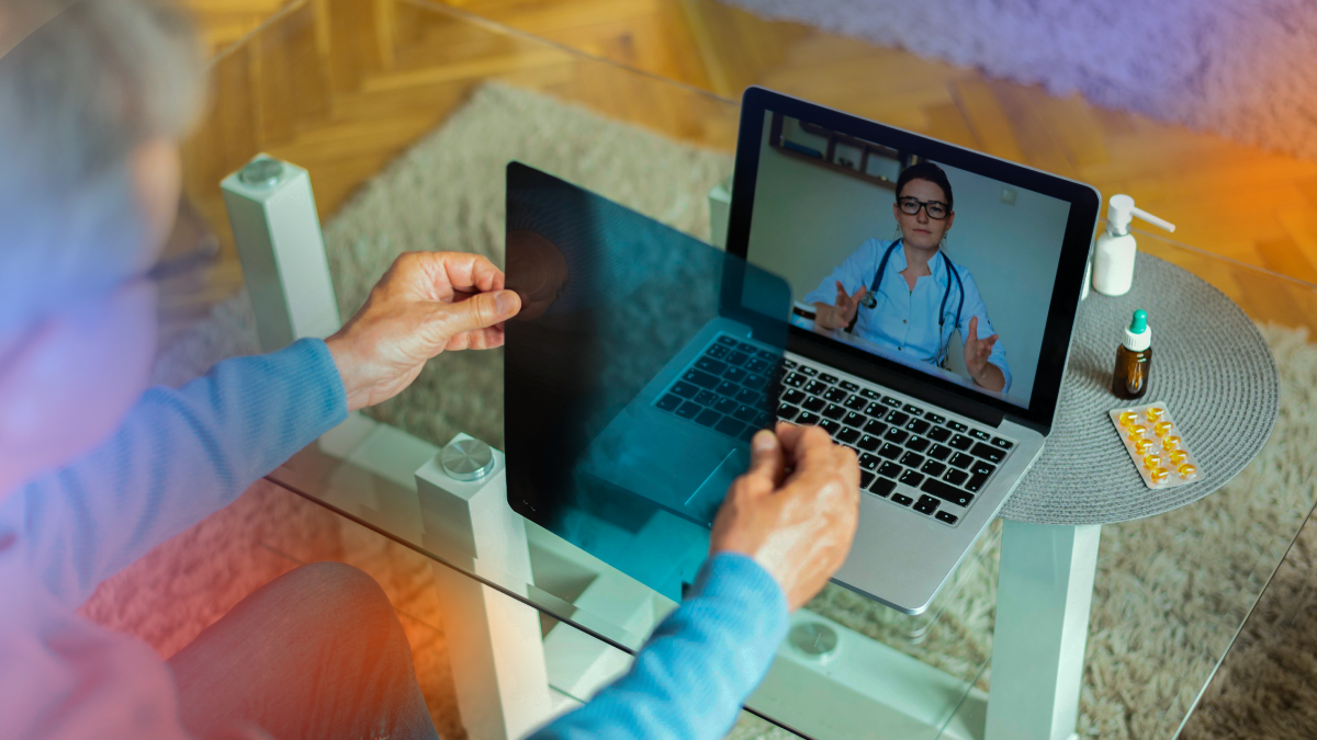 Patient participating in a virtual consultation with a healthcare professional through a laptop while reviewing a medical image.