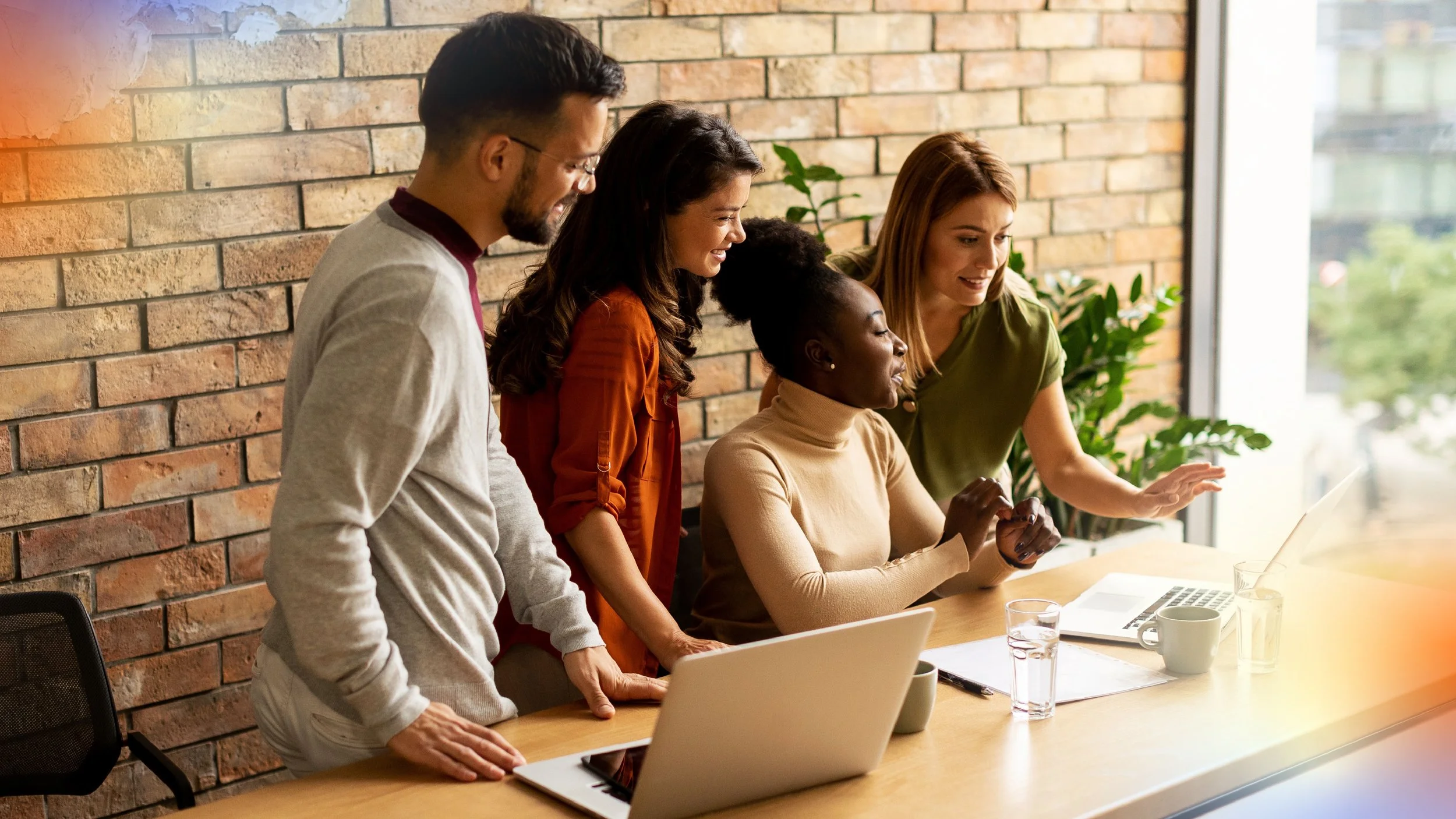 Team of professionals reviewing information together around a laptop, representing teamwork, strategic alignment and collaborative decision-making.